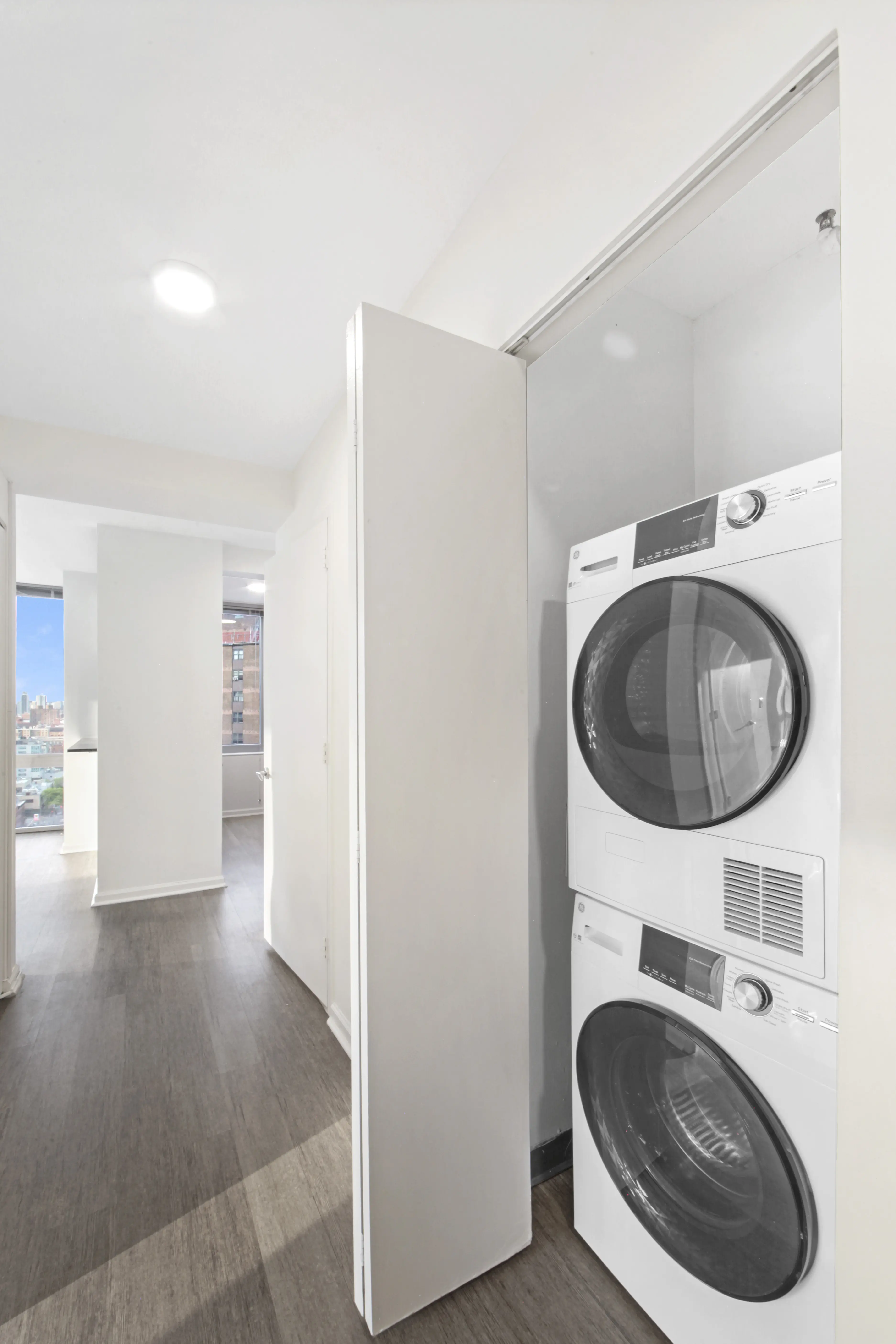 A small apartment features a white washer and dryer side by side in a limited space.