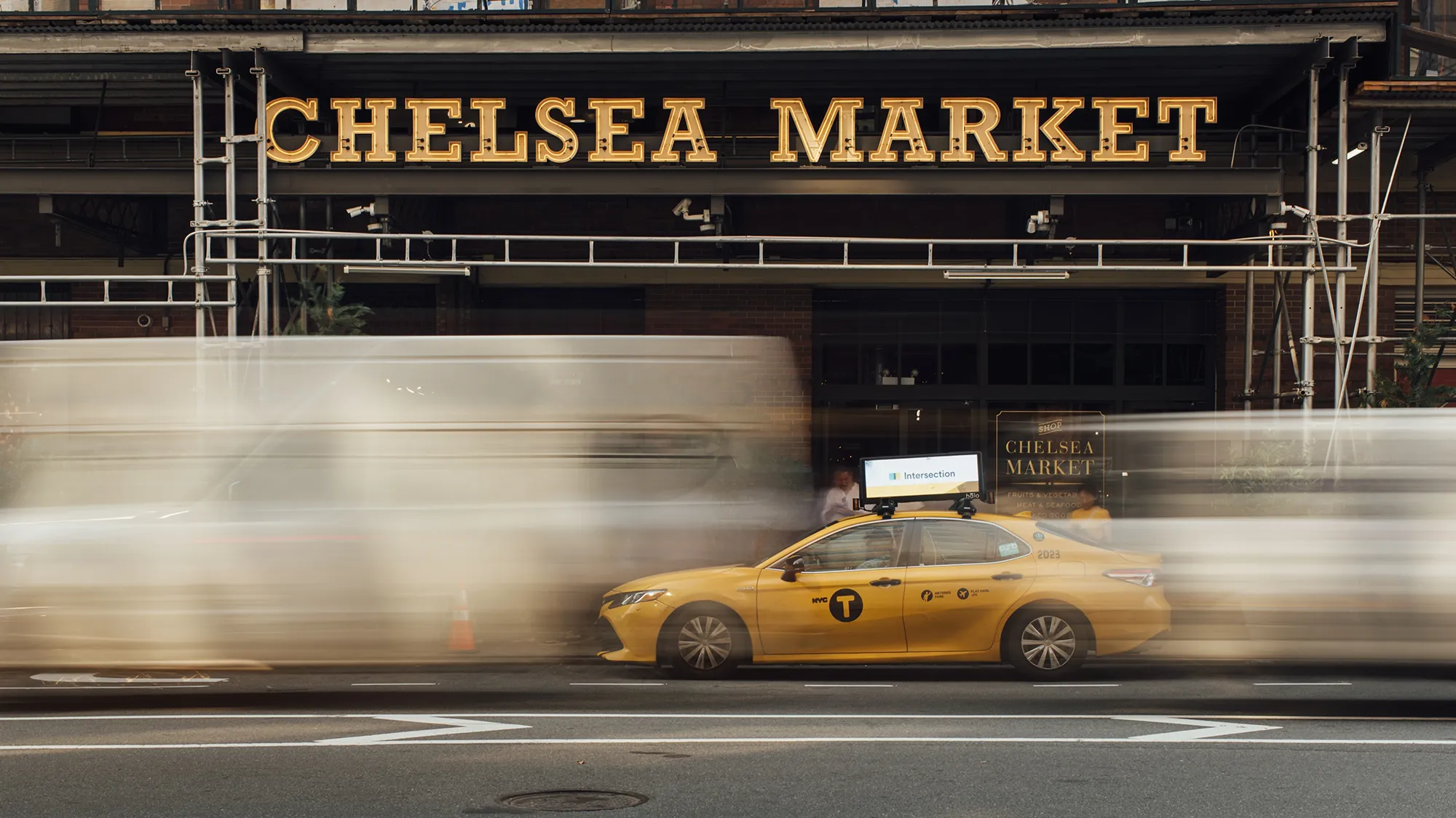 A yellow taxi cab parked in front of Chelsea Market, showcasing the vibrant urban atmosphere of the area.