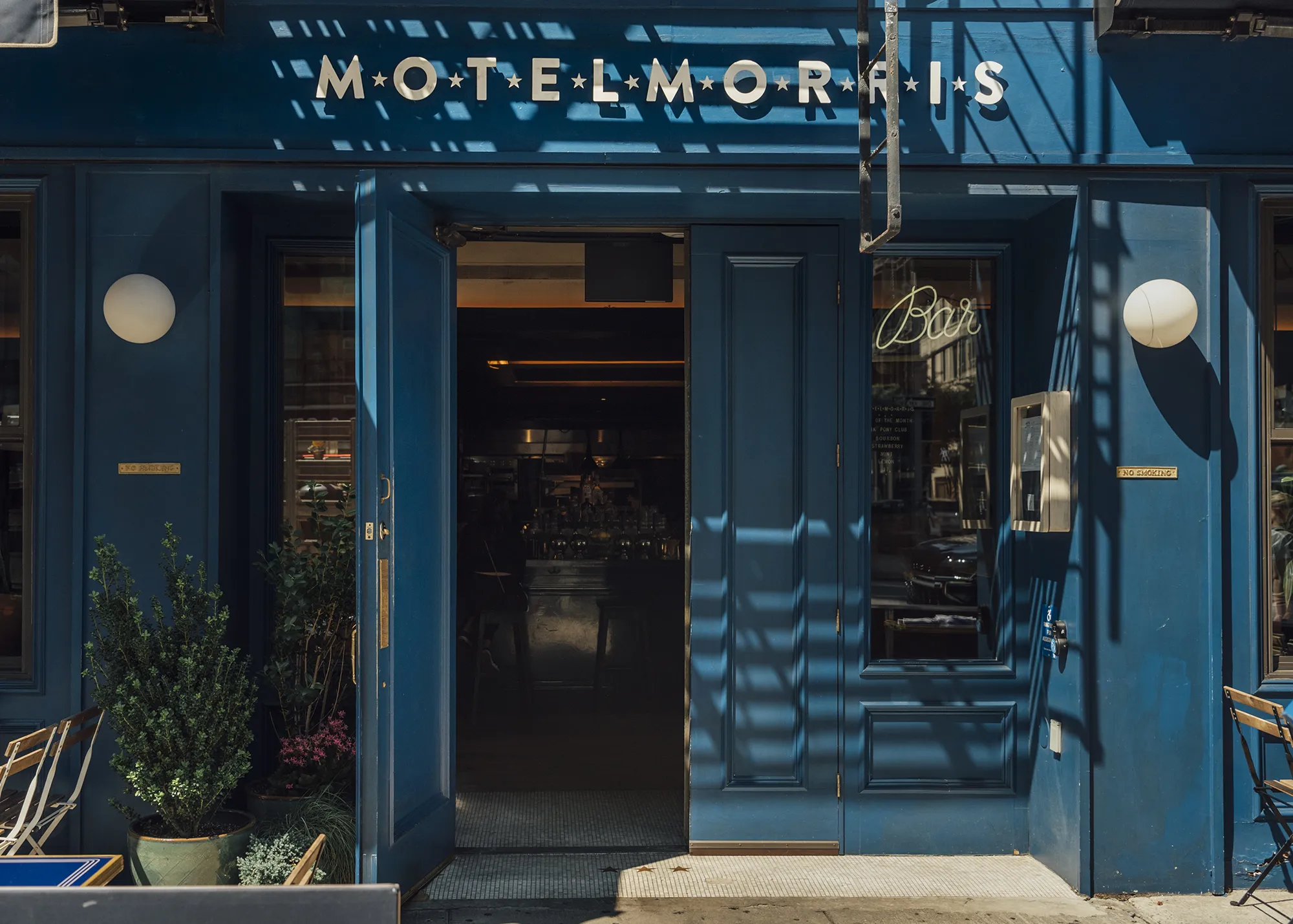 The entrance to Motel Morris in New York City, featuring a bright sign and welcoming doorway.