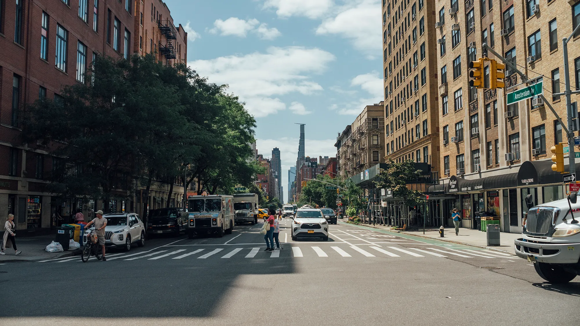 A city street featuring a tall building in the background, showcasing urban architecture and bustling activity.