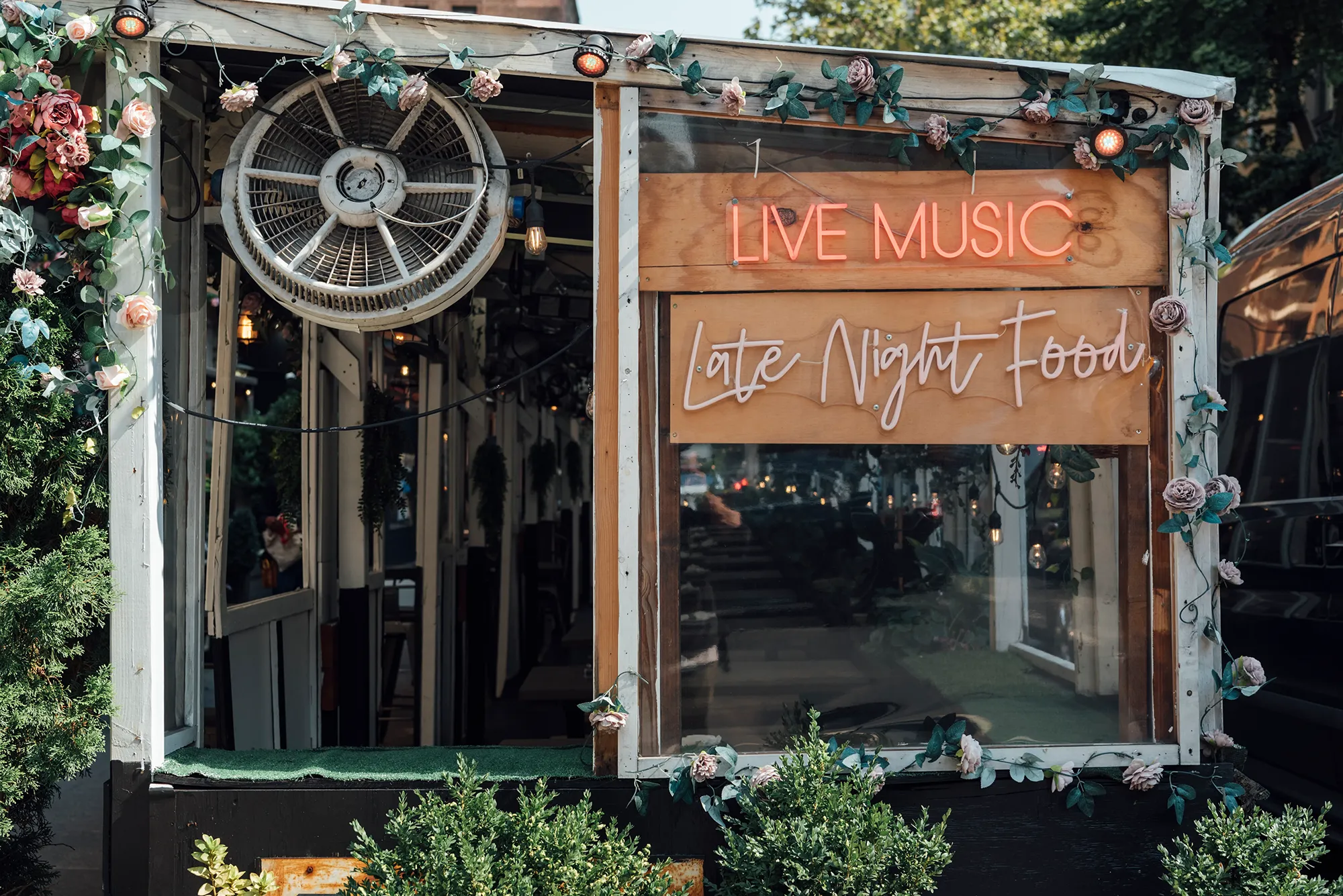 Live band performing in a garden setting, with audience enjoying the music under a clear blue sky.
