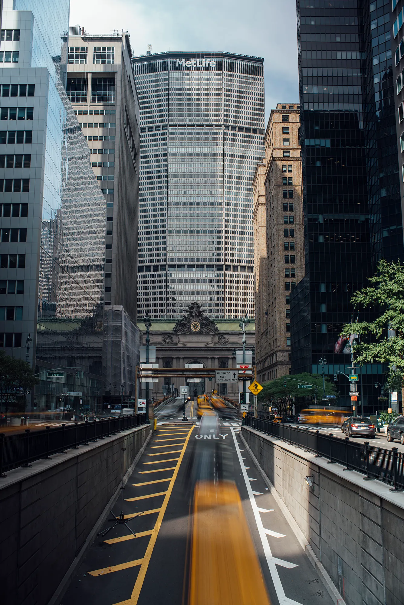 A bright yellow school bus driving along a road surrounded by greenery.