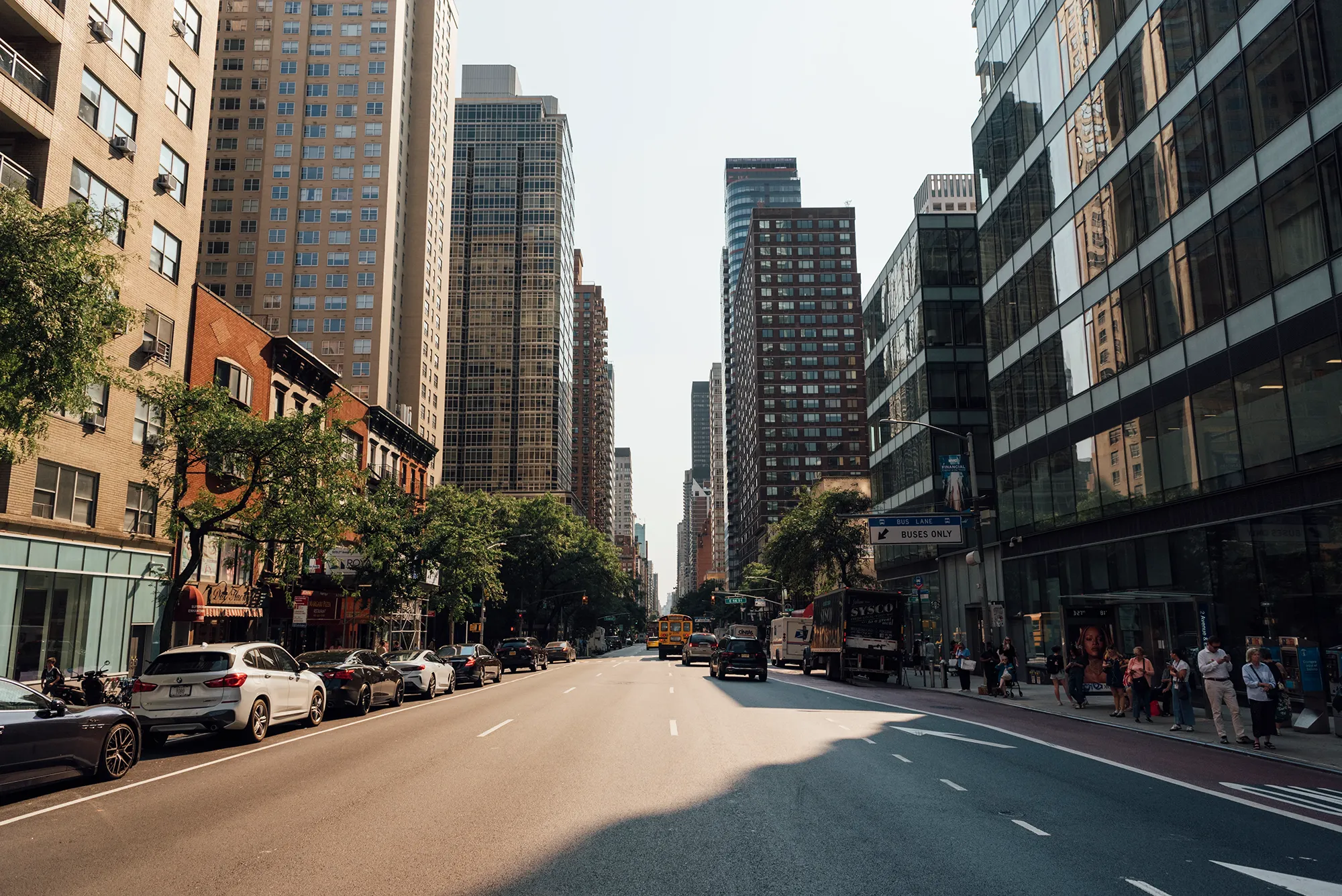 A busy city street filled with cars and pedestrians walking along the sidewalks.