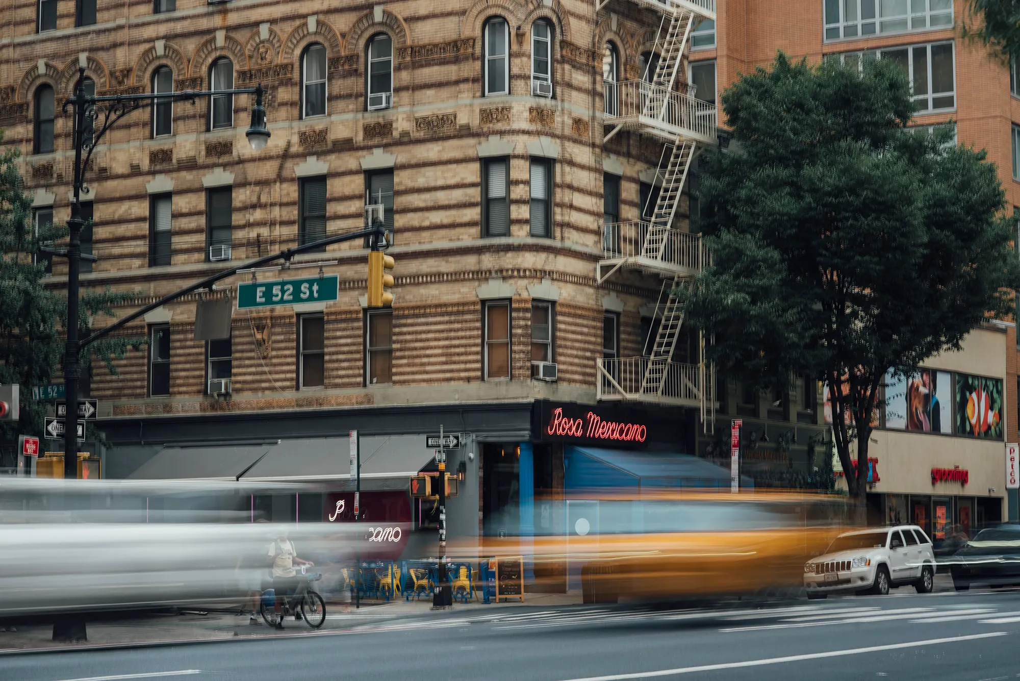 Blurry street scene with indistinct buildings and vehicles, suggesting a busy urban environment.