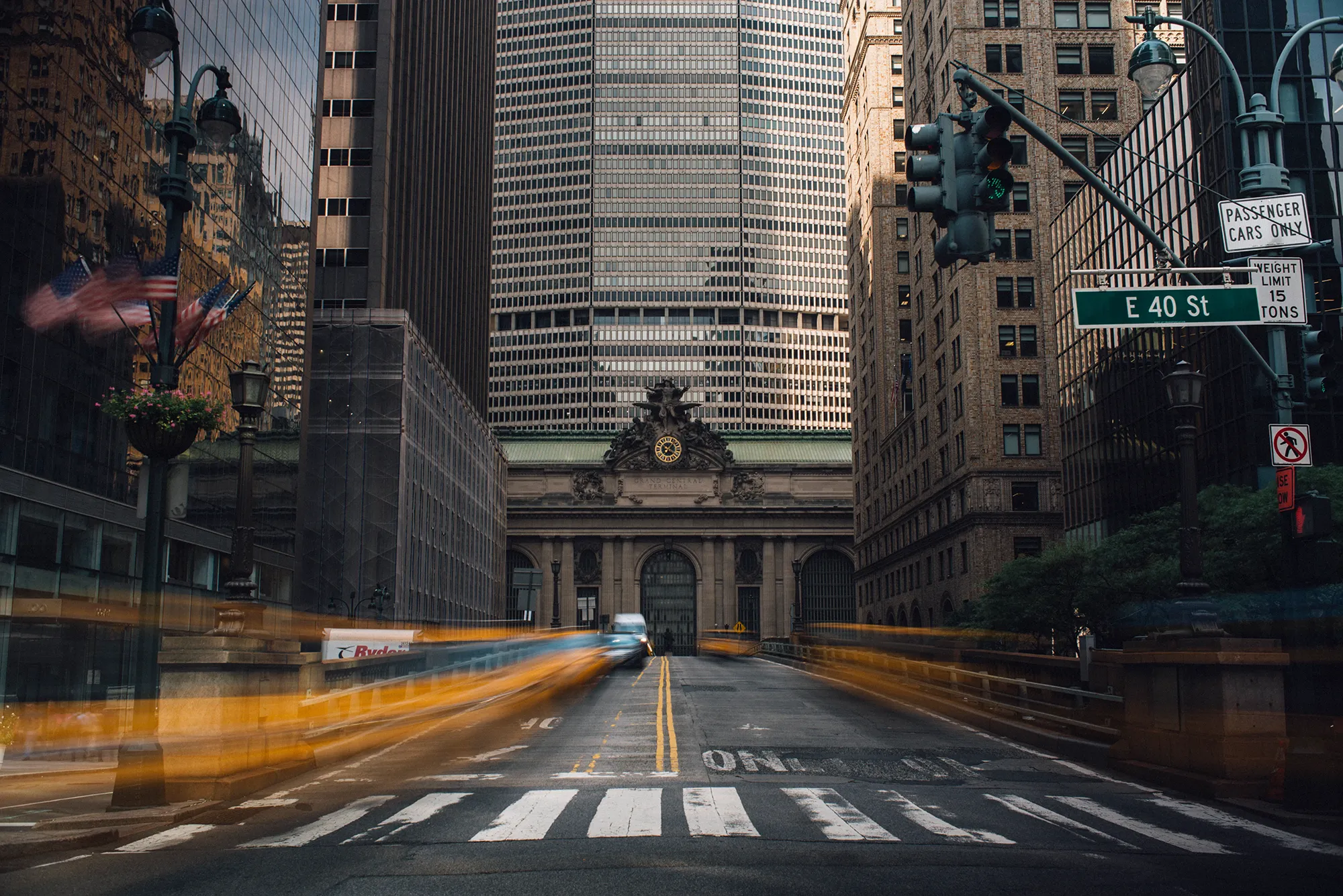 A bright yellow school bus driving along a road surrounded by greenery.