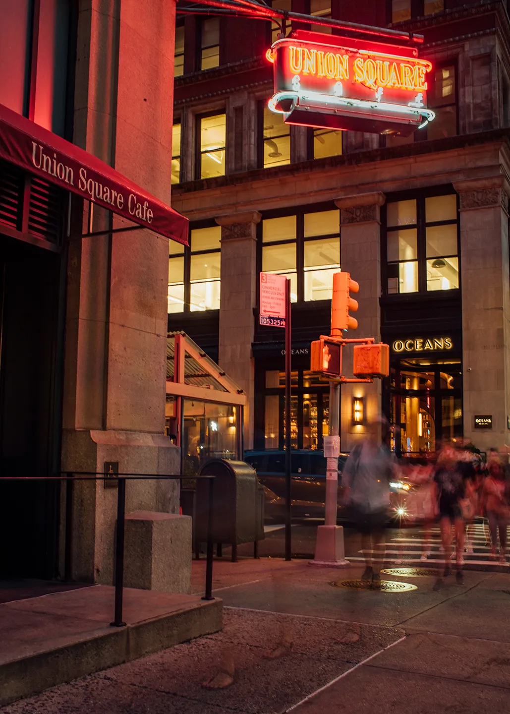 A bright red neon sign illuminated on the exterior of a building at night.