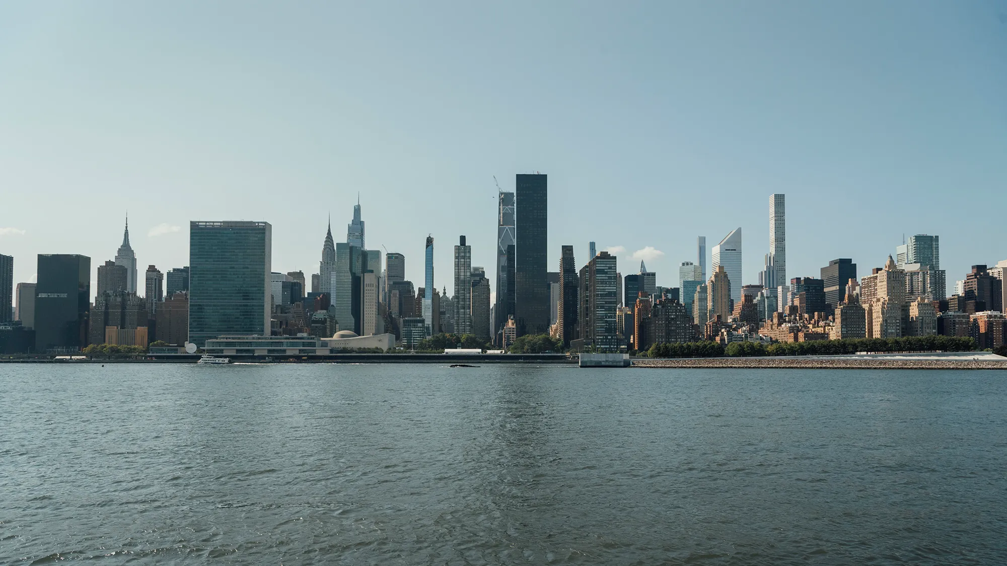 A serene body of water reflecting the sky, surrounded by lush greenery and distant hills.
