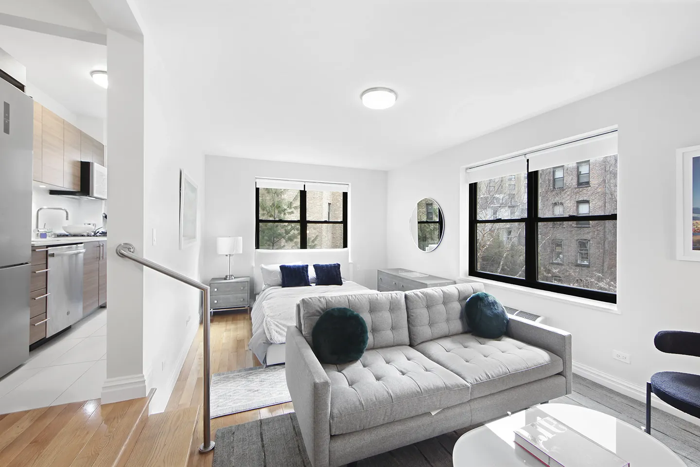 A small apartment featuring a couch, bed, and kitchen area, showcasing a cozy living space.