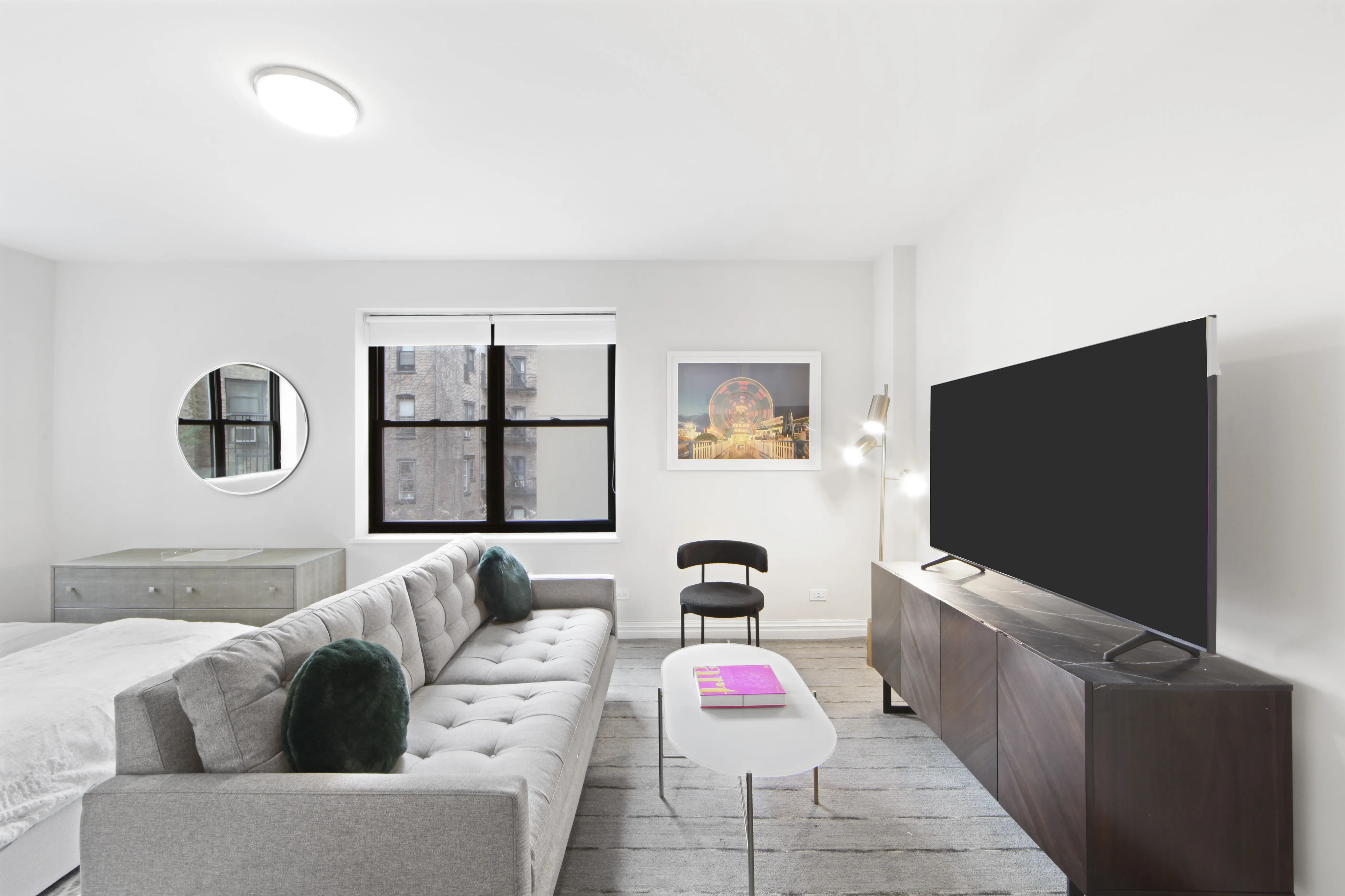 A clean white room featuring a couch, coffee table, and television, creating a cozy and modern living space.