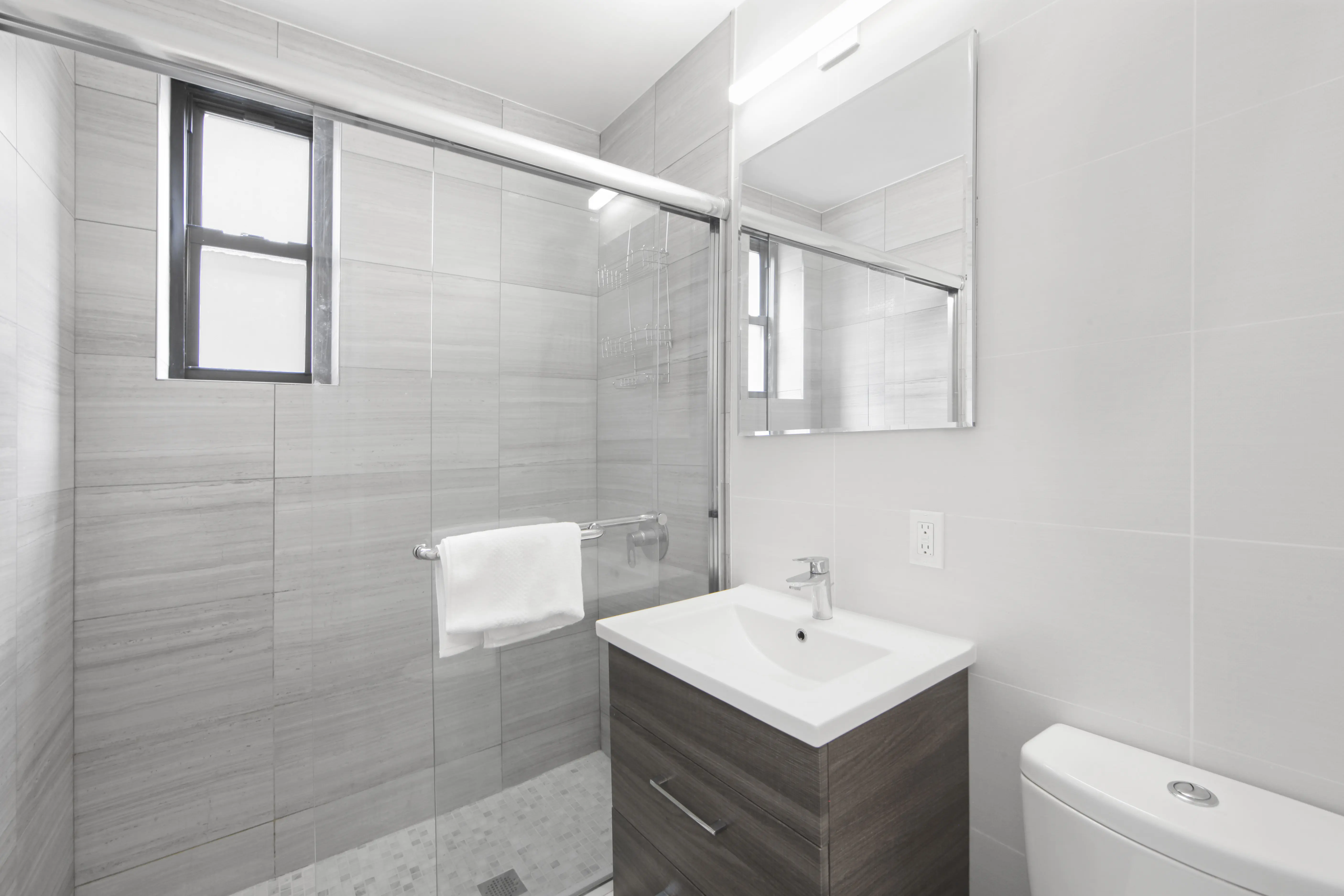 A bathroom featuring a shower stall, sink, and toilet, designed for functional and efficient use of space.