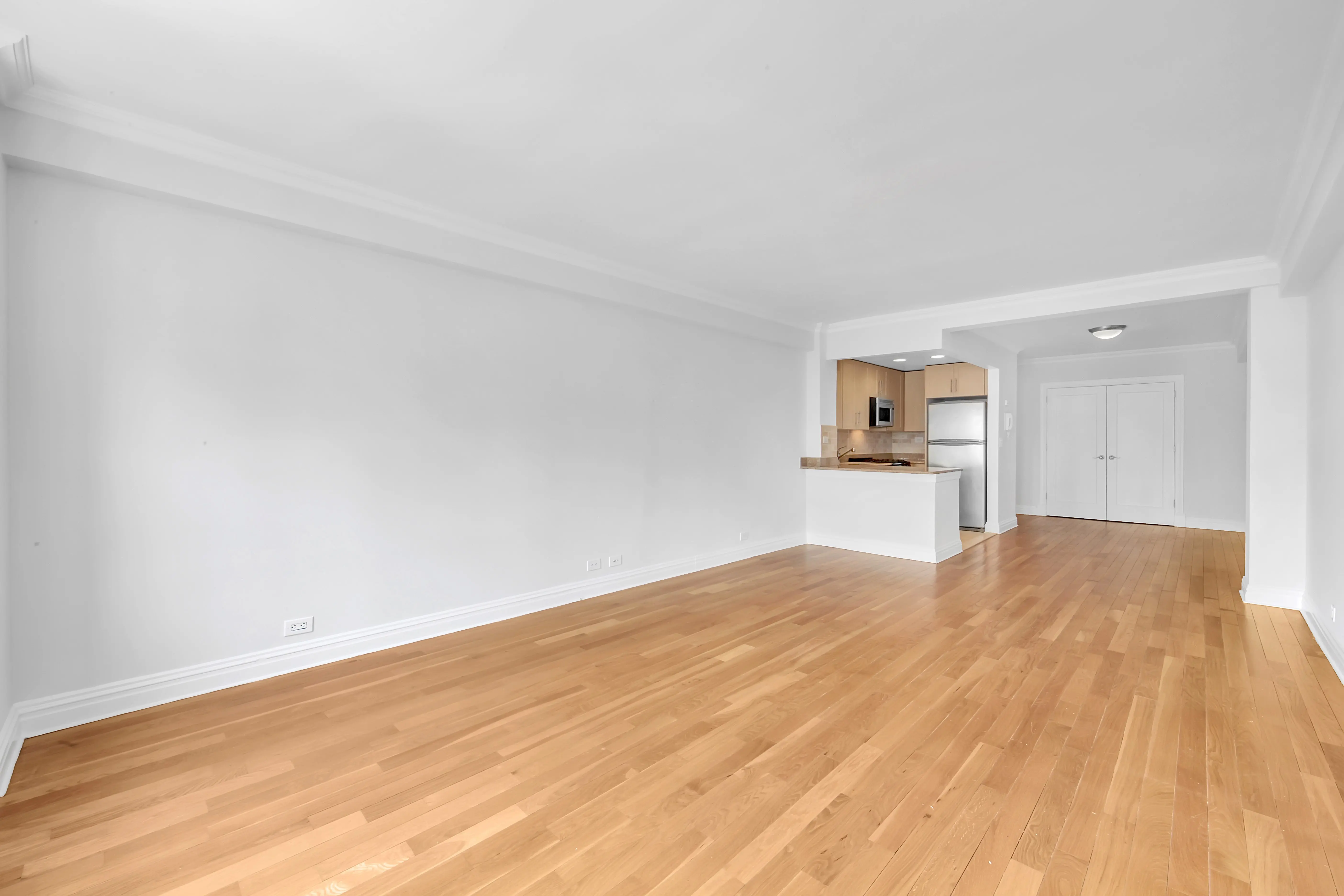 An empty room featuring hardwood floors and white walls, creating a bright and spacious atmosphere.