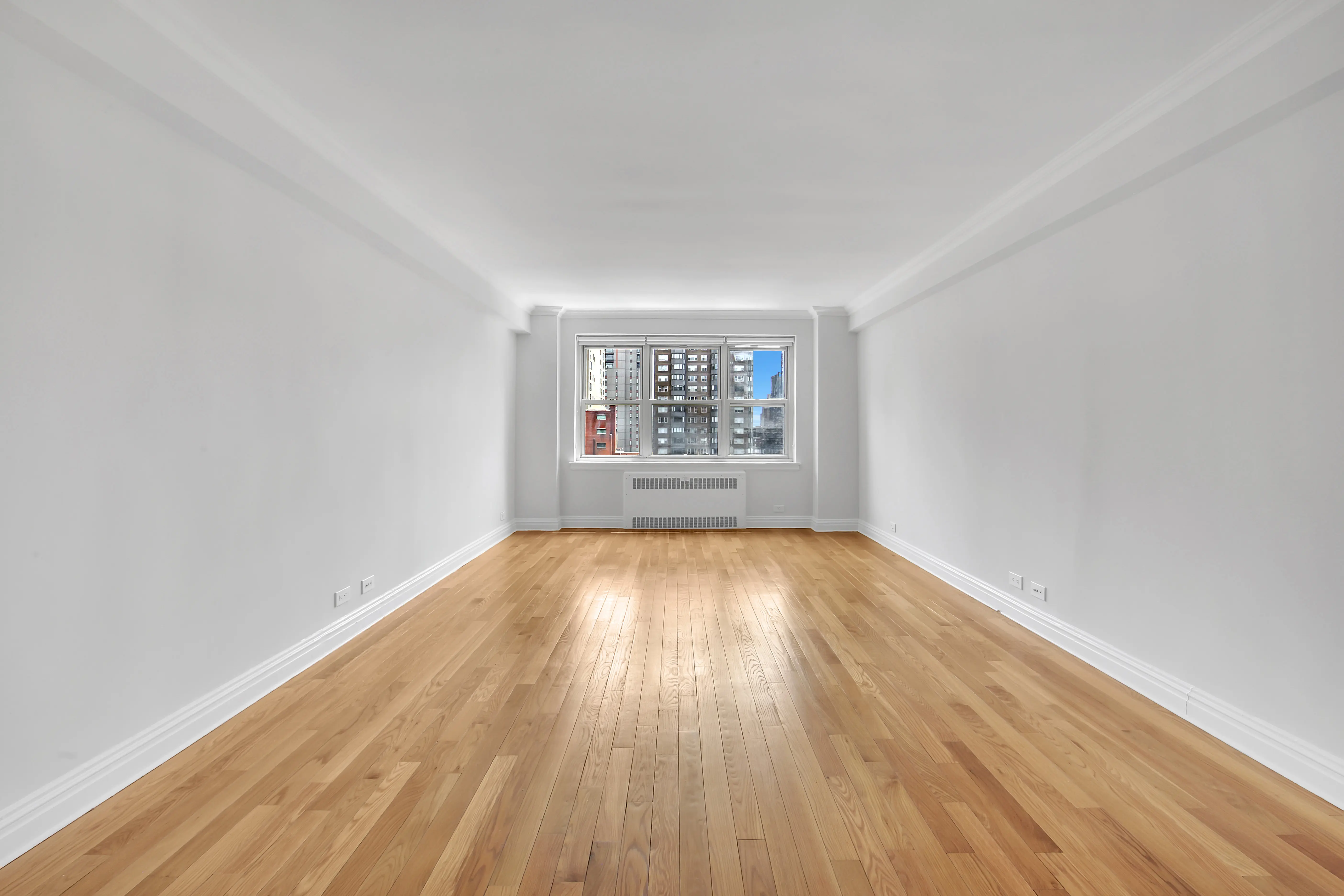 An empty room featuring hardwood floors and white walls, creating a bright and spacious atmosphere.
