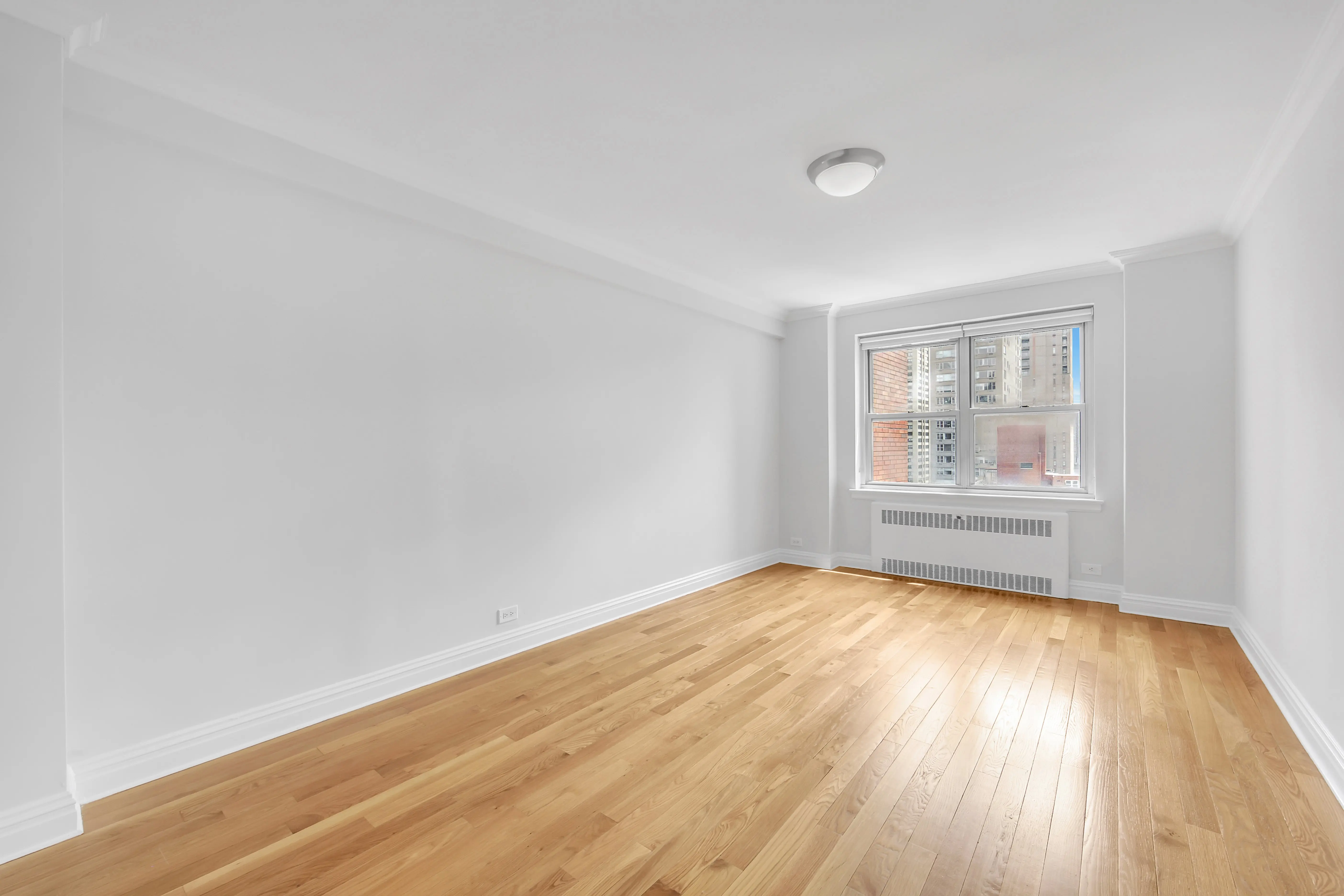 An empty room featuring hardwood floors and white walls, creating a bright and spacious atmosphere.