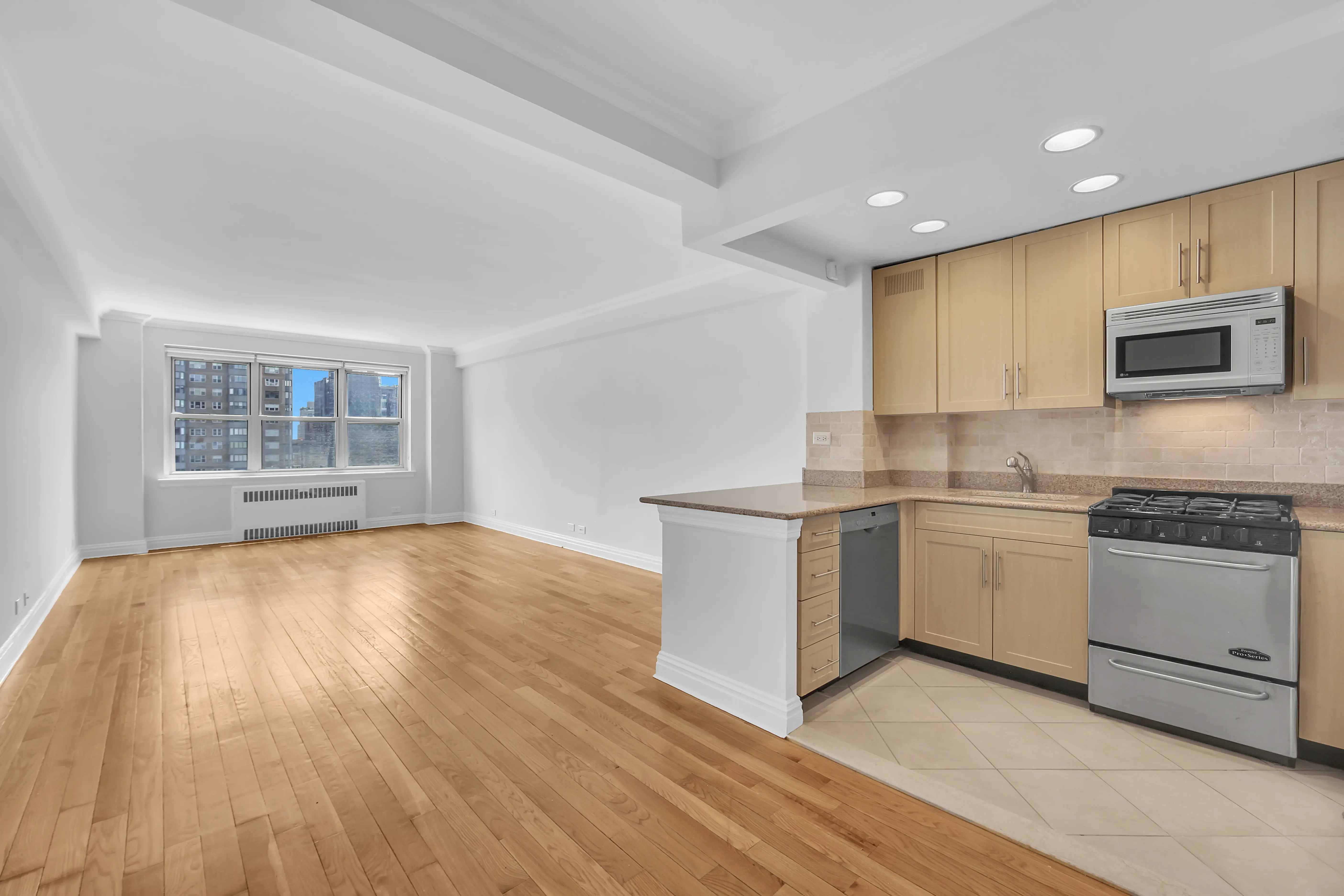 An empty kitchen featuring hardwood floors and a stove, showcasing a clean and spacious environment.