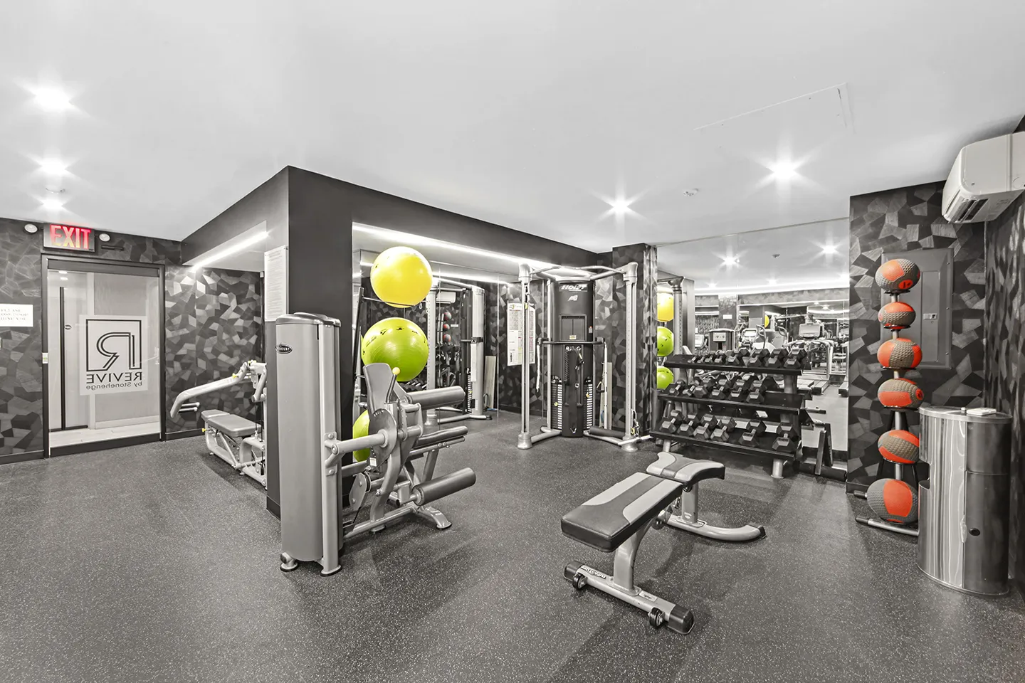 Interior of a gym with weights, exercise machines, and mirrors reflecting the workout space.