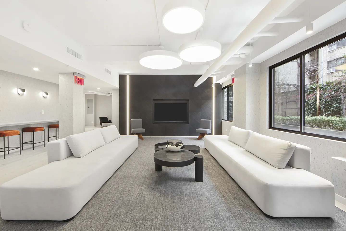 A modern office featuring white couches and a television, creating a sleek and inviting workspace atmosphere.