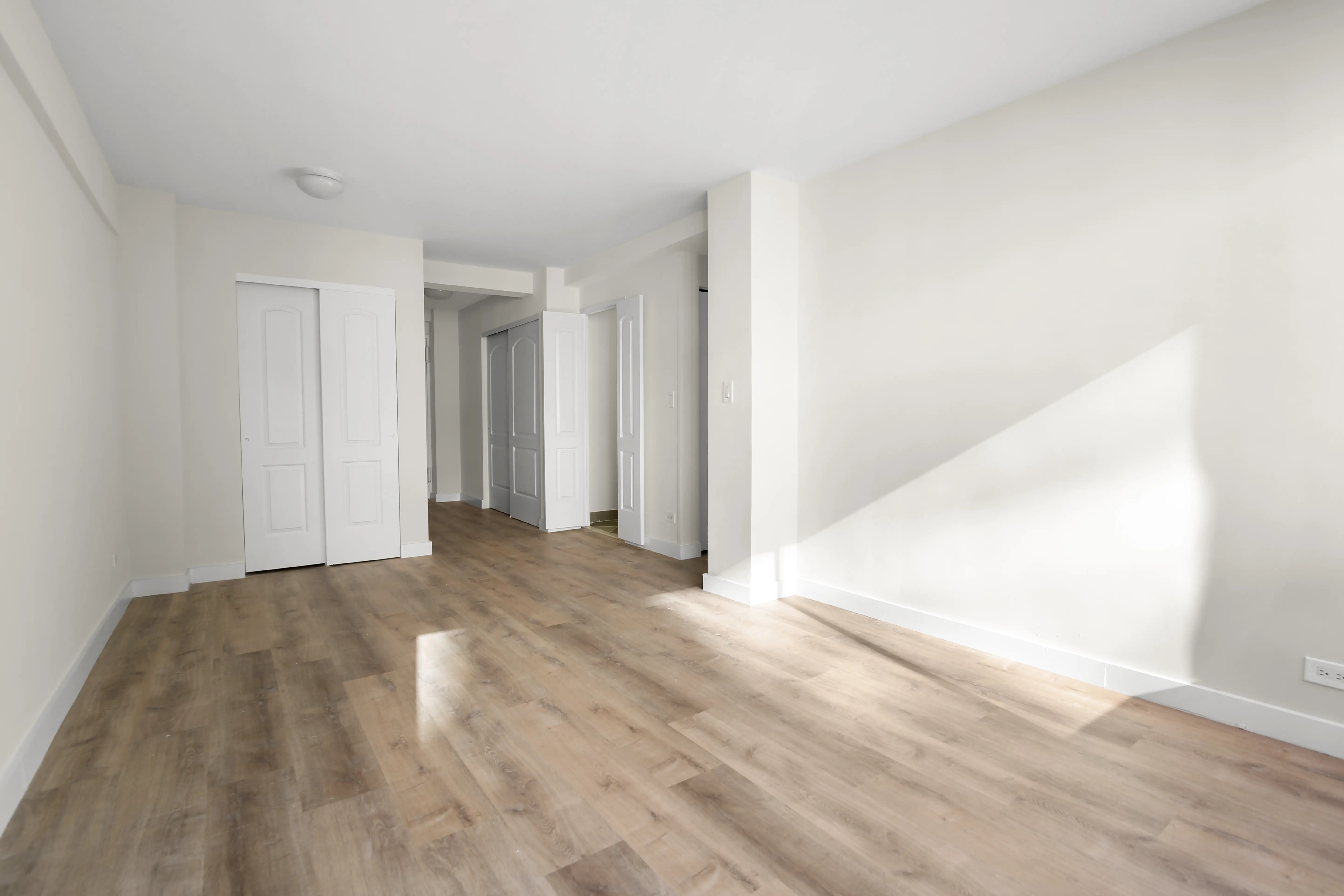 An unoccupied room showcasing hardwood flooring and white walls, emphasizing simplicity and openness.