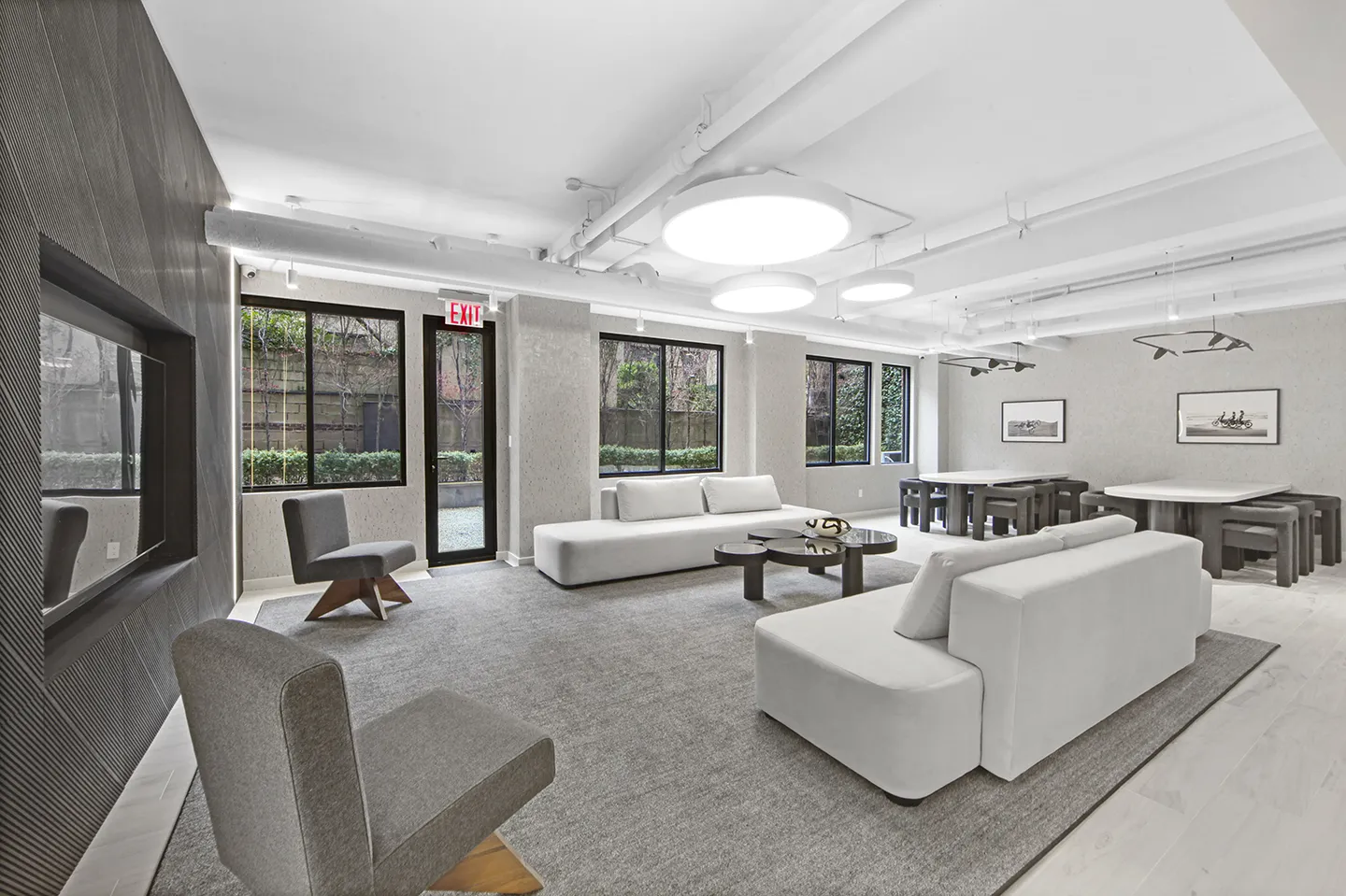 A sleek modern office featuring white furniture and a large television mounted on the wall.