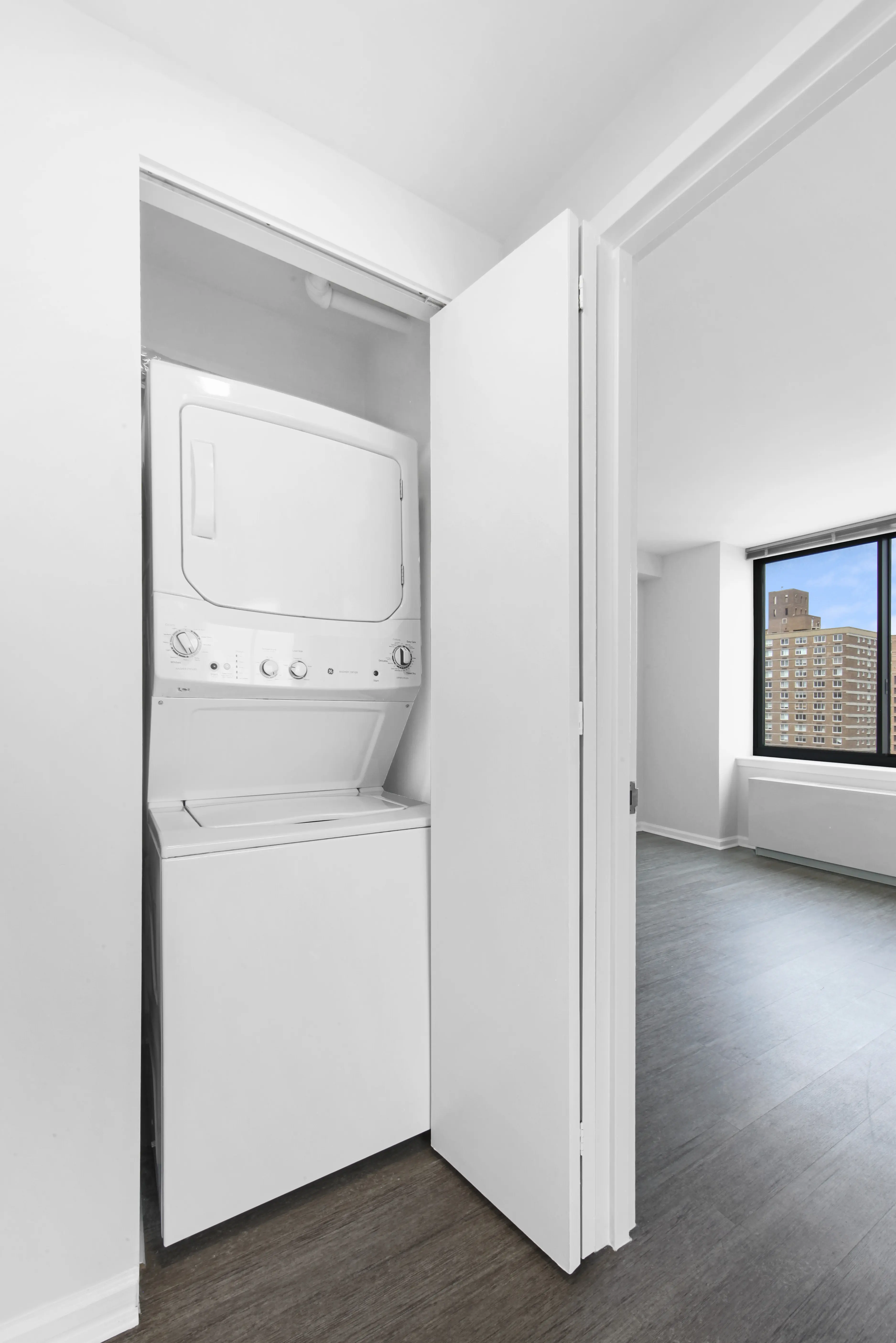 A small apartment features a white washer and dryer side by side in a limited space.