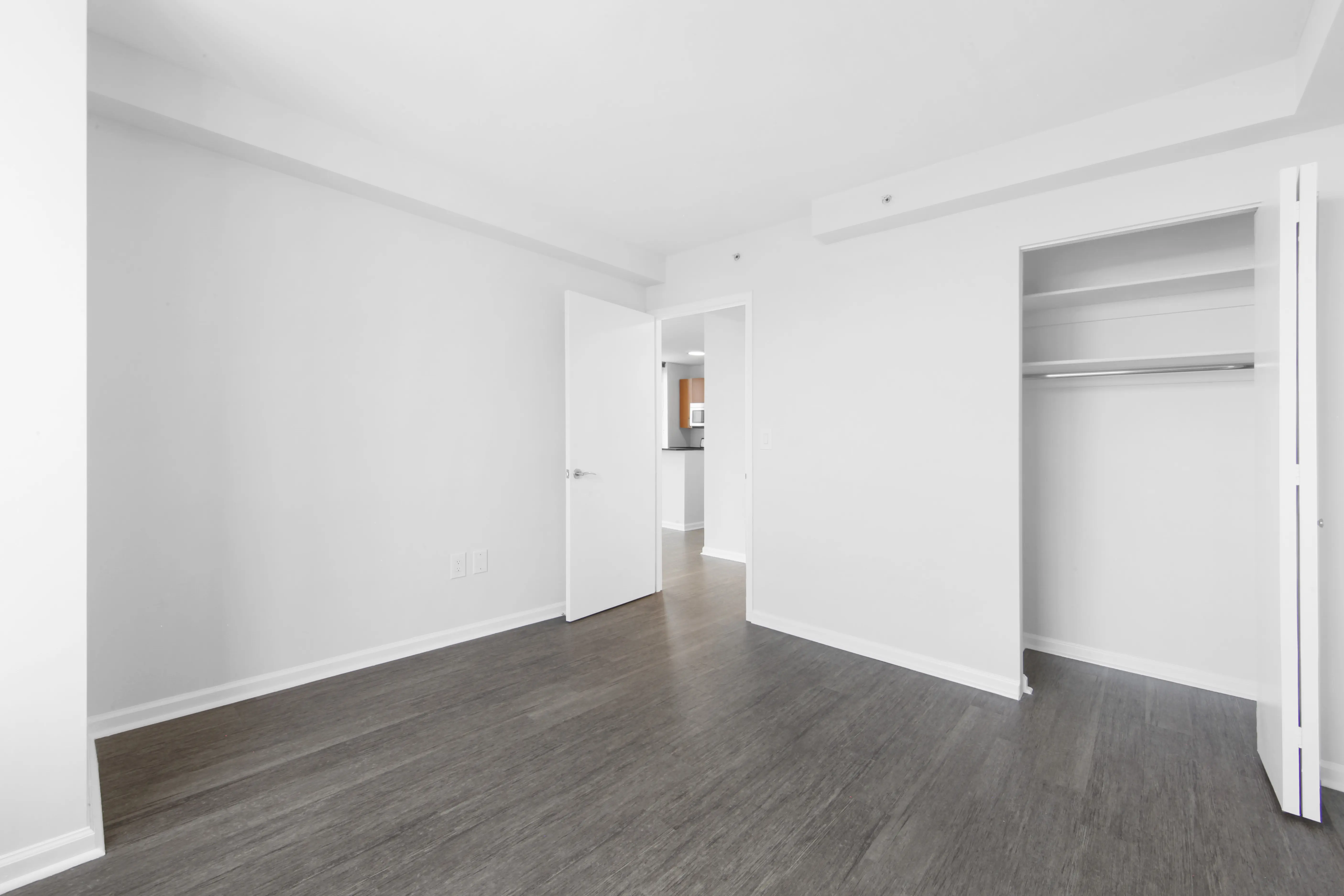 An unoccupied room showcasing white walls and natural wooden floors, offering a minimalist and airy feel.