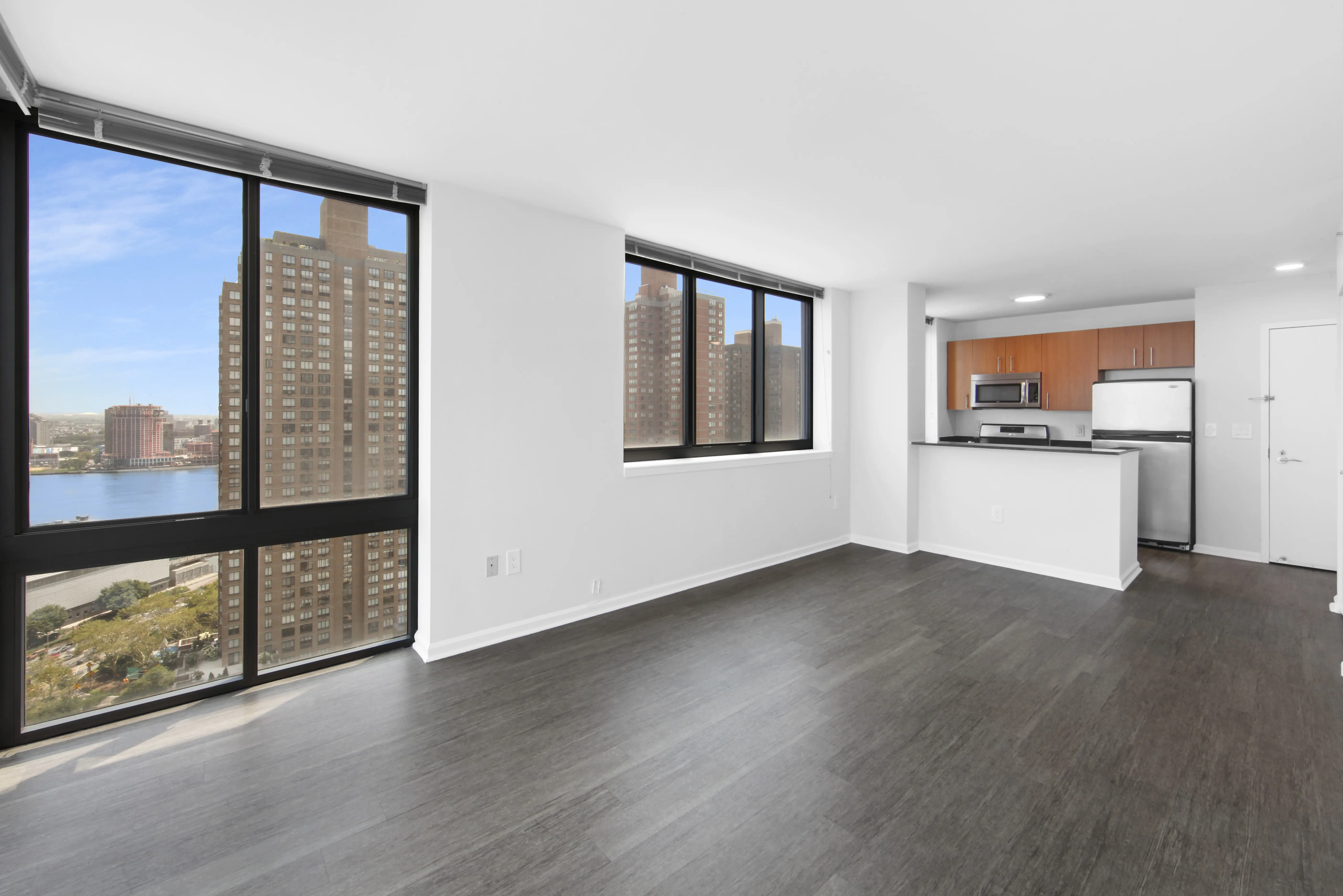 A vacant apartment showcasing hardwood floors and expansive windows, creating a bright and open atmosphere.
