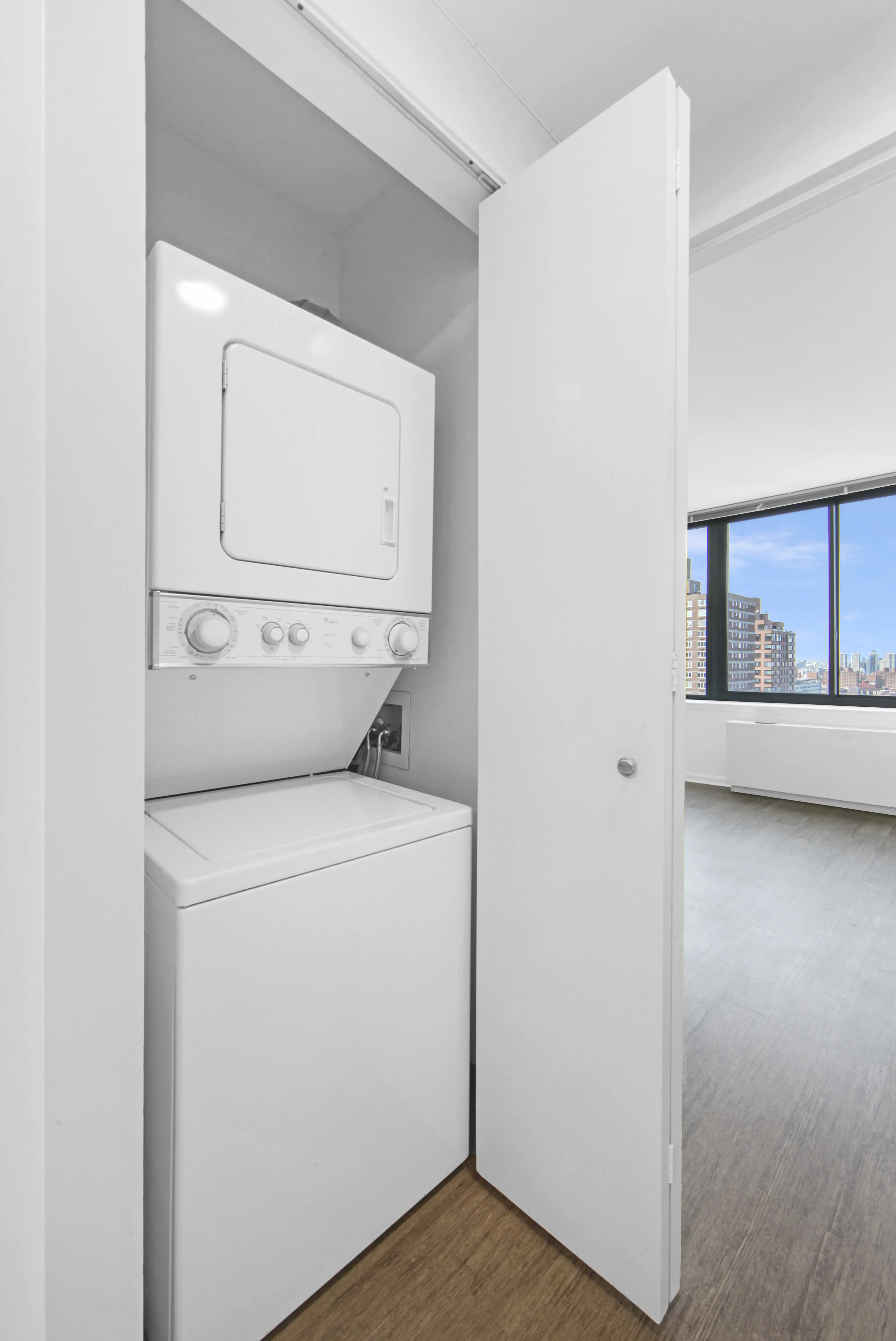 A compact white washer and dryer set in a small apartment laundry area.