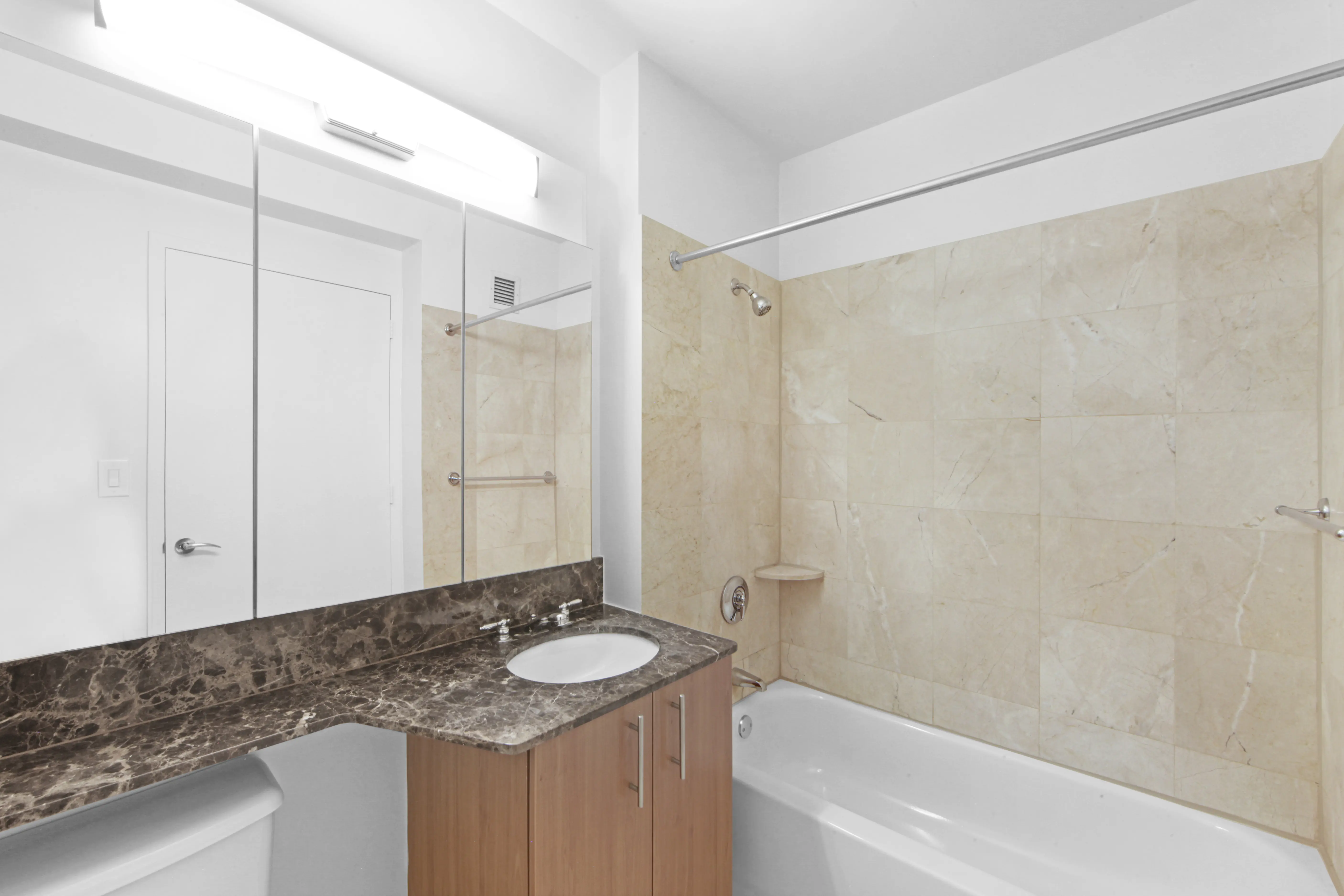 A well-lit bathroom with a sink, toilet, and shower, highlighting a simple and functional layout for daily use.