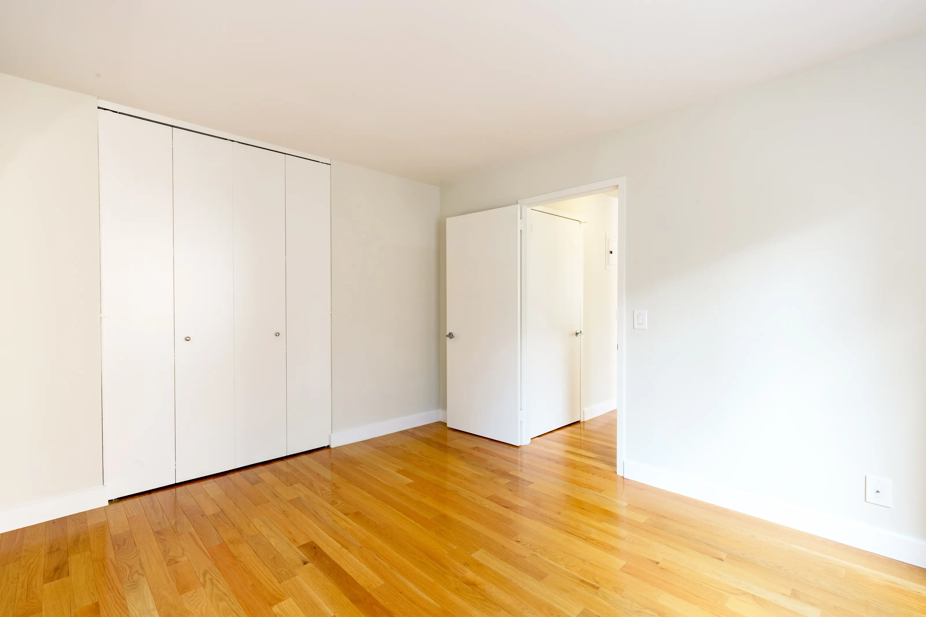 A room featuring white closets and polished hardwood floors, creating a bright and inviting atmosphere.