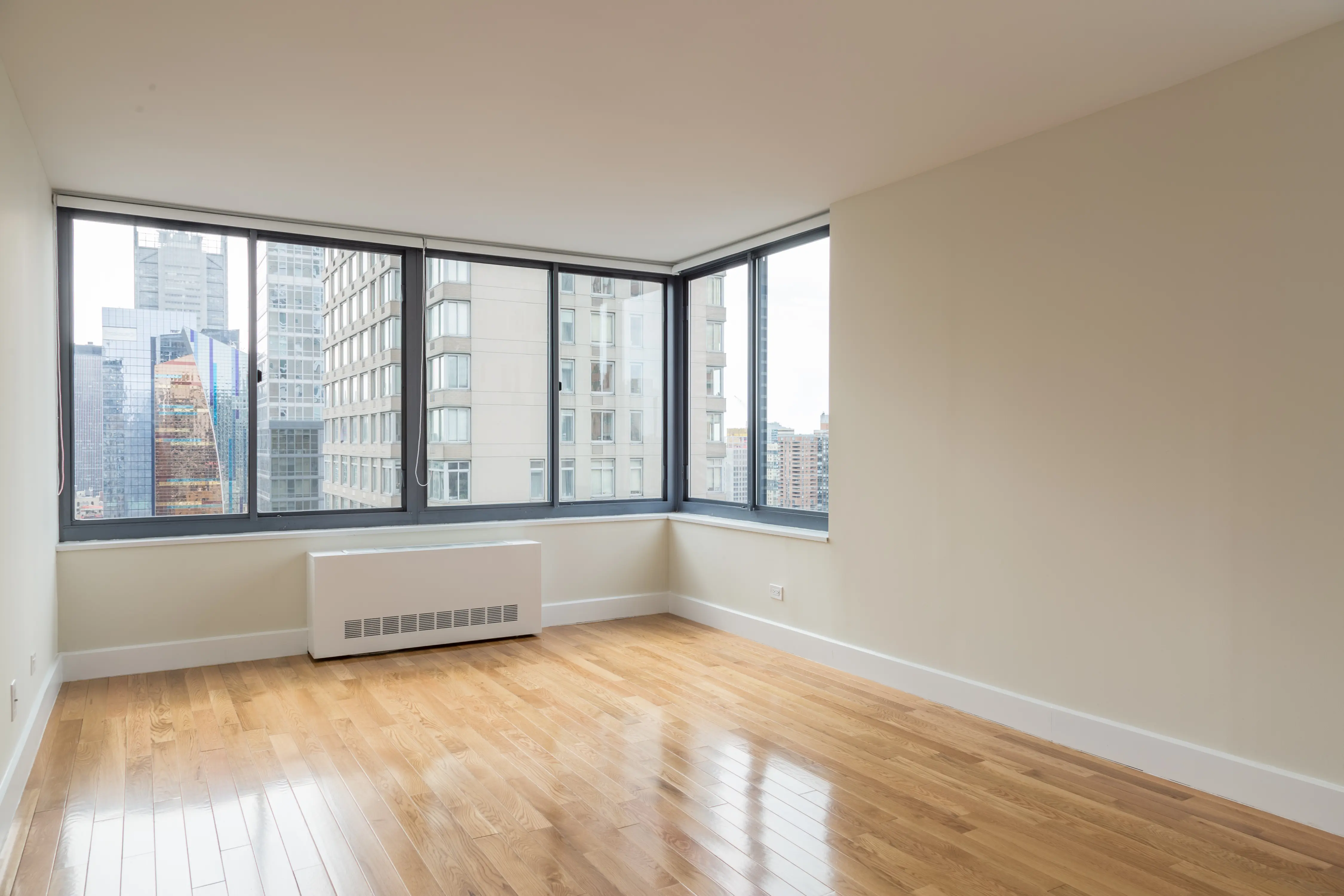 An empty room featuring hardwood floors and large windows allowing natural light to enter.