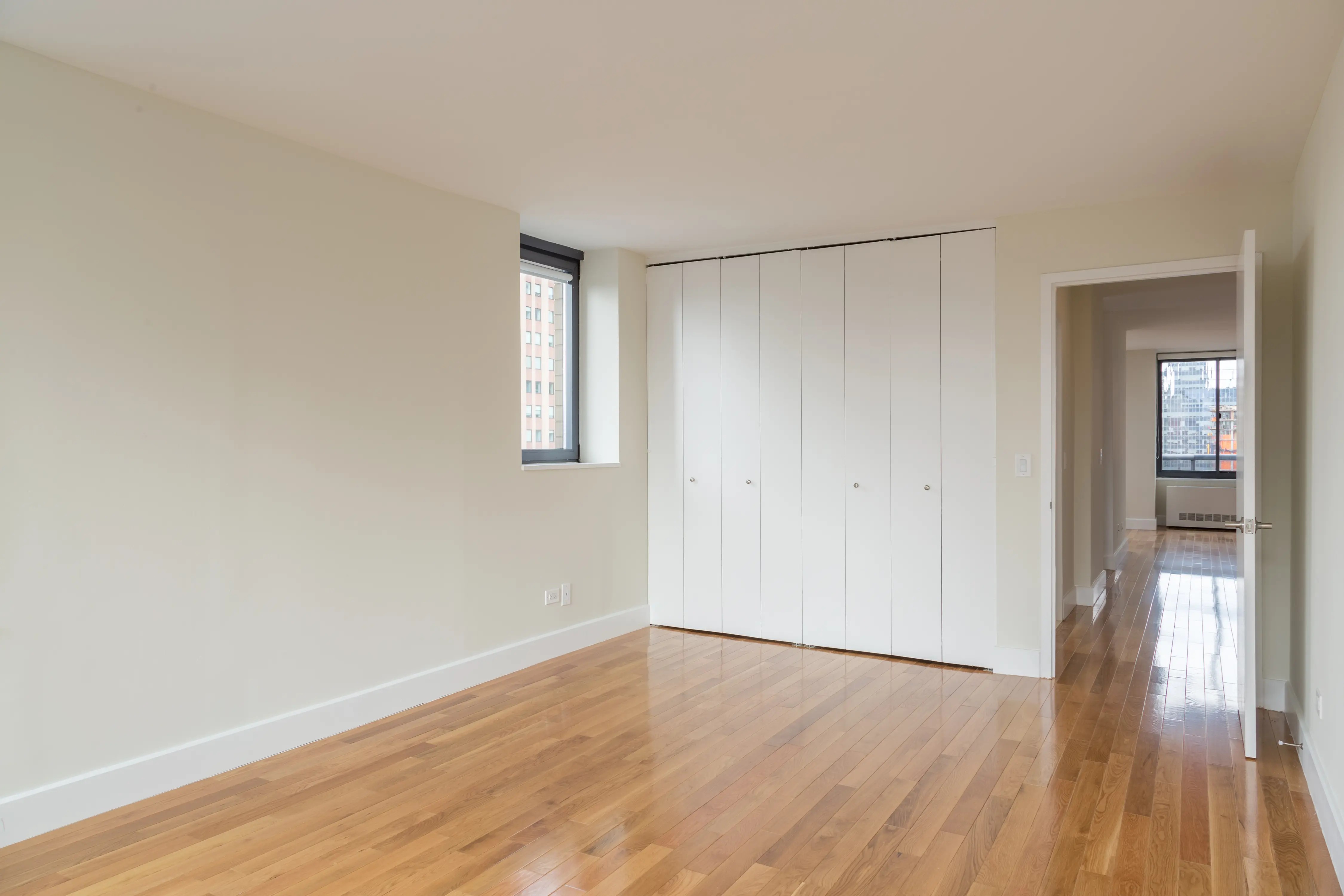 A vacant room with polished hardwood floors and sleek white cabinets, emphasizing a clean and modern design.