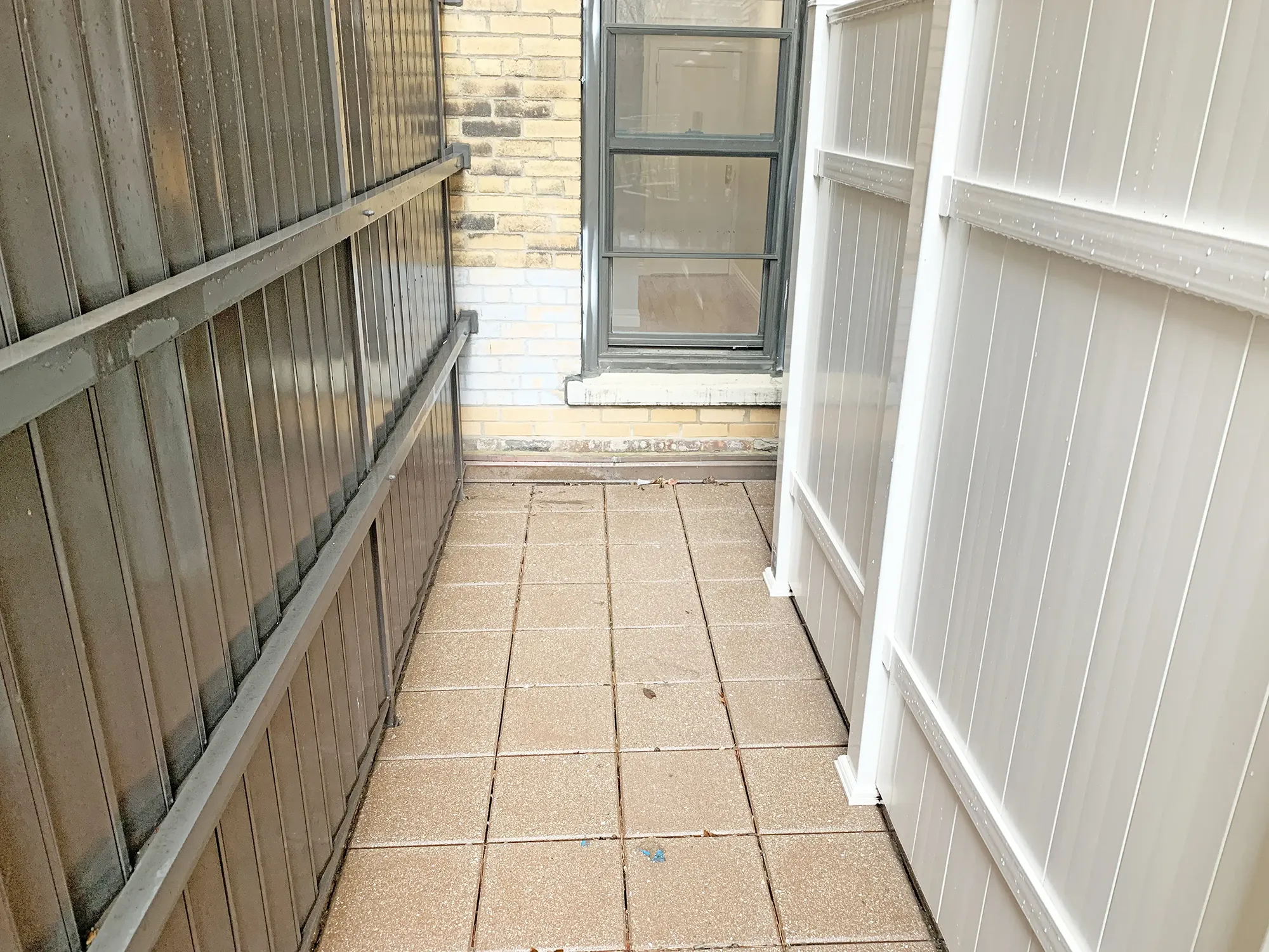A narrow hallway featuring a door on one side and a window on the opposite wall, illuminated by natural light.