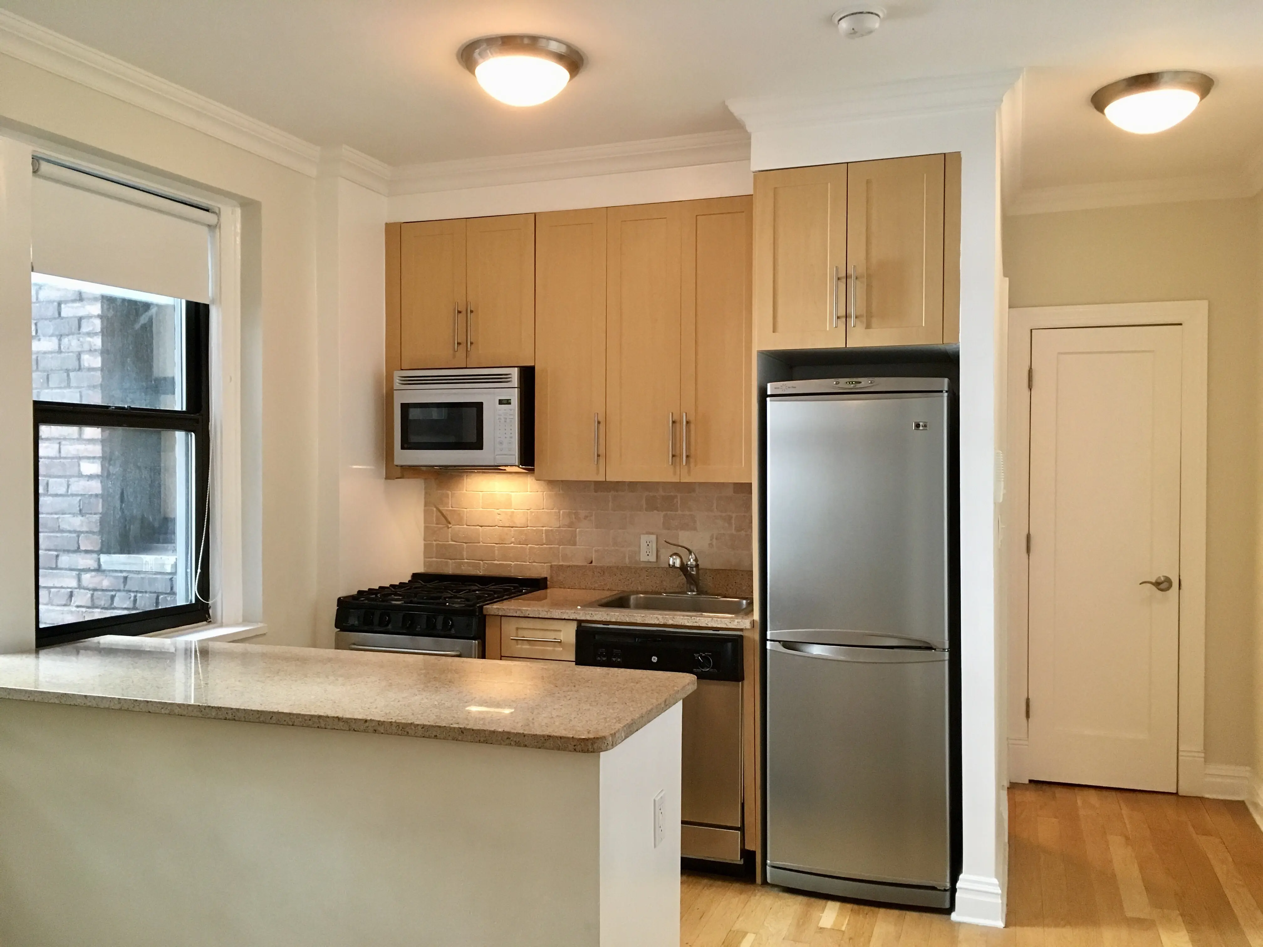 A small kitchen featuring stainless steel appliances and wooden cabinets, creating a modern yet warm atmosphere.