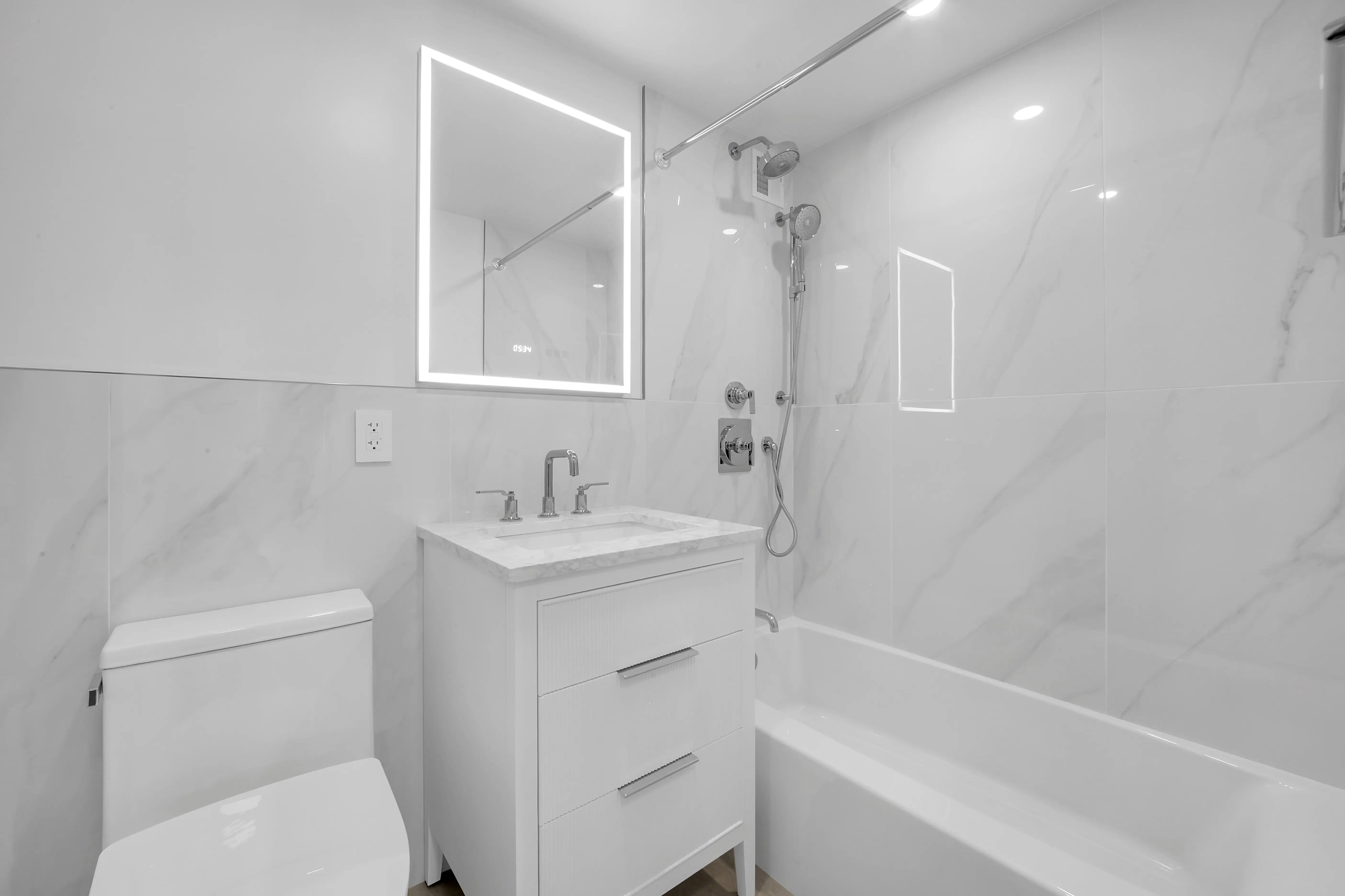 A bright white bathroom showcasing a sink, toilet, and bathtub in a modern design.