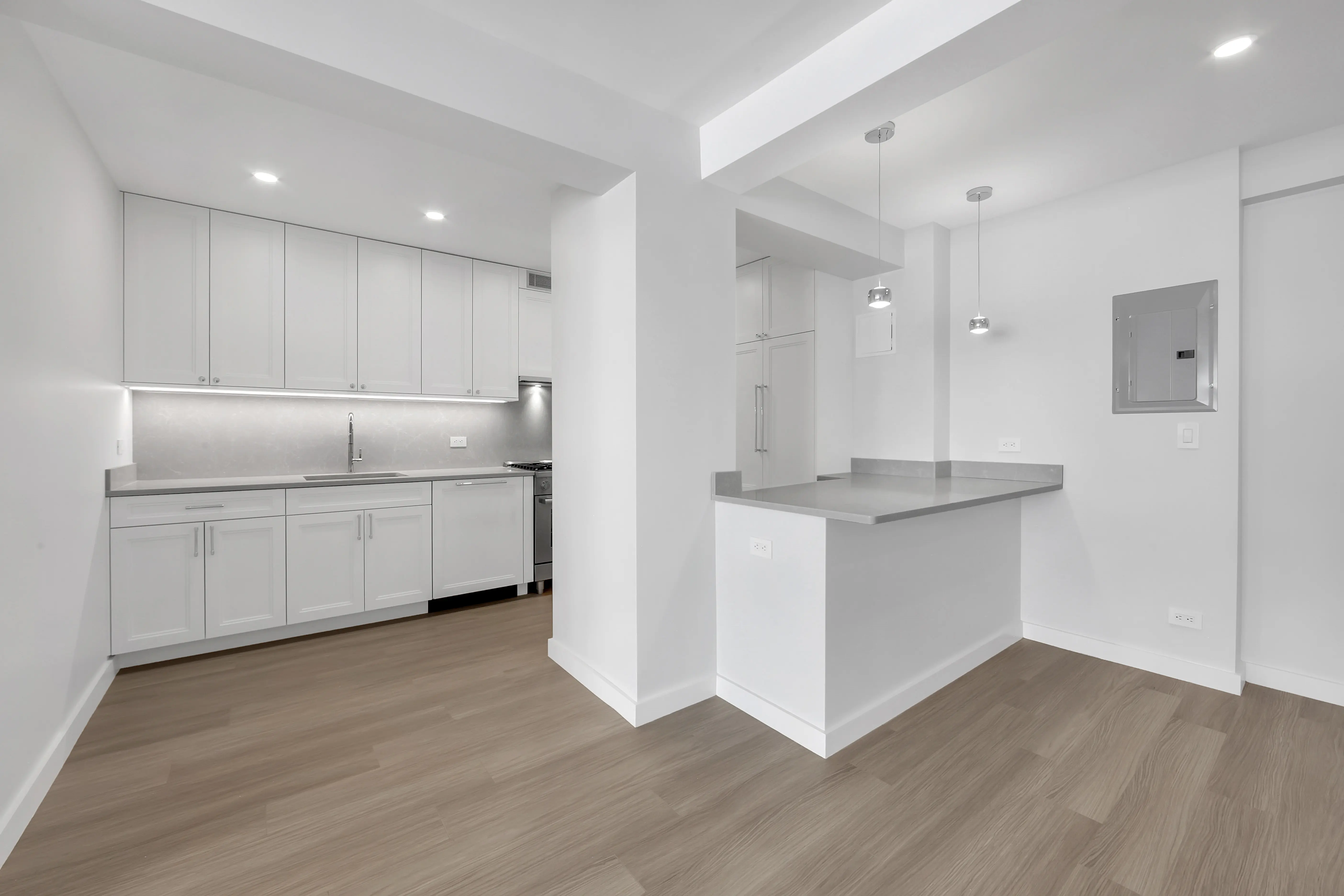 A bright white kitchen featuring wood floors and sleek white cabinets, creating a clean and modern aesthetic.