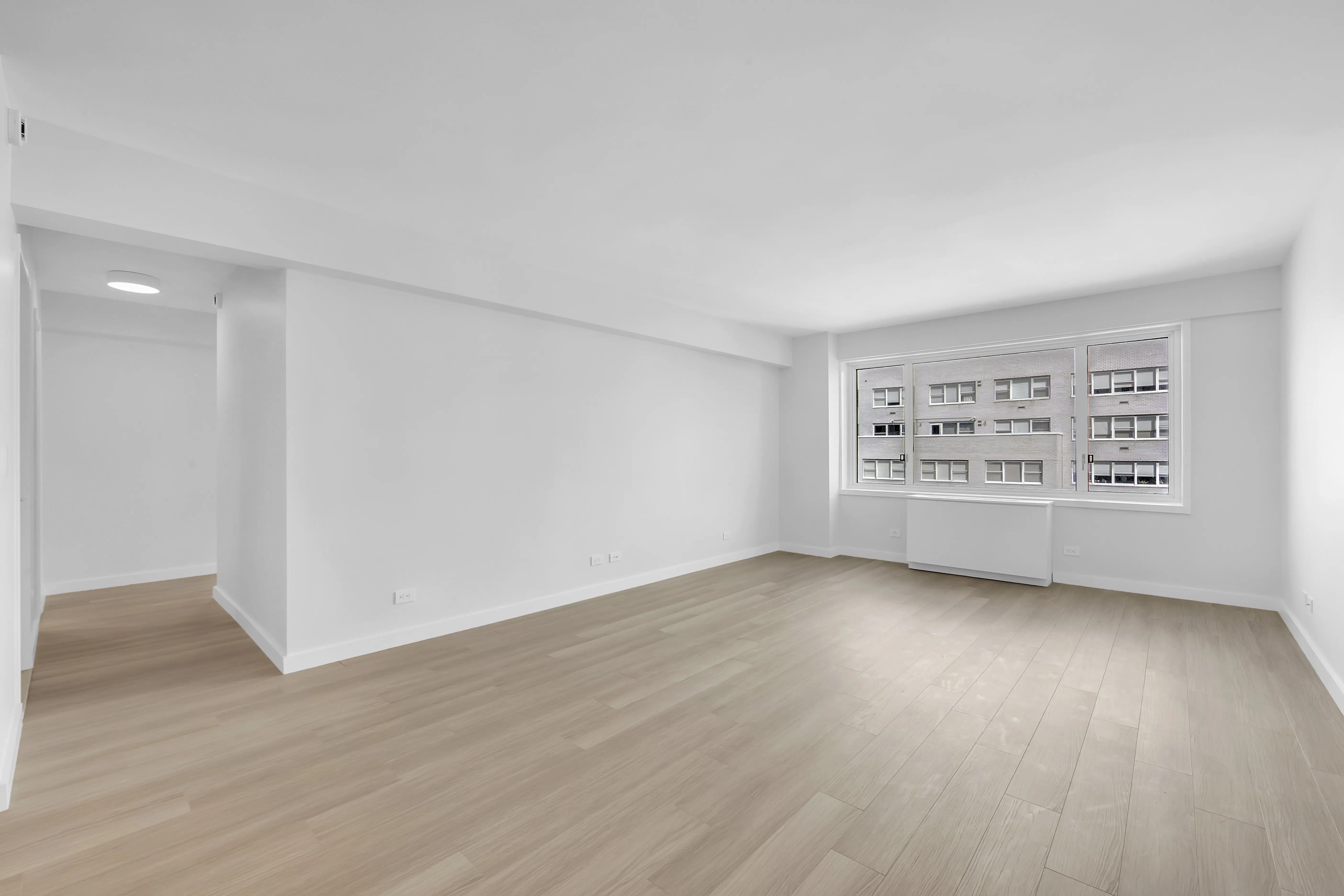 An empty room featuring hardwood floors and white walls, creating a bright and spacious atmosphere.