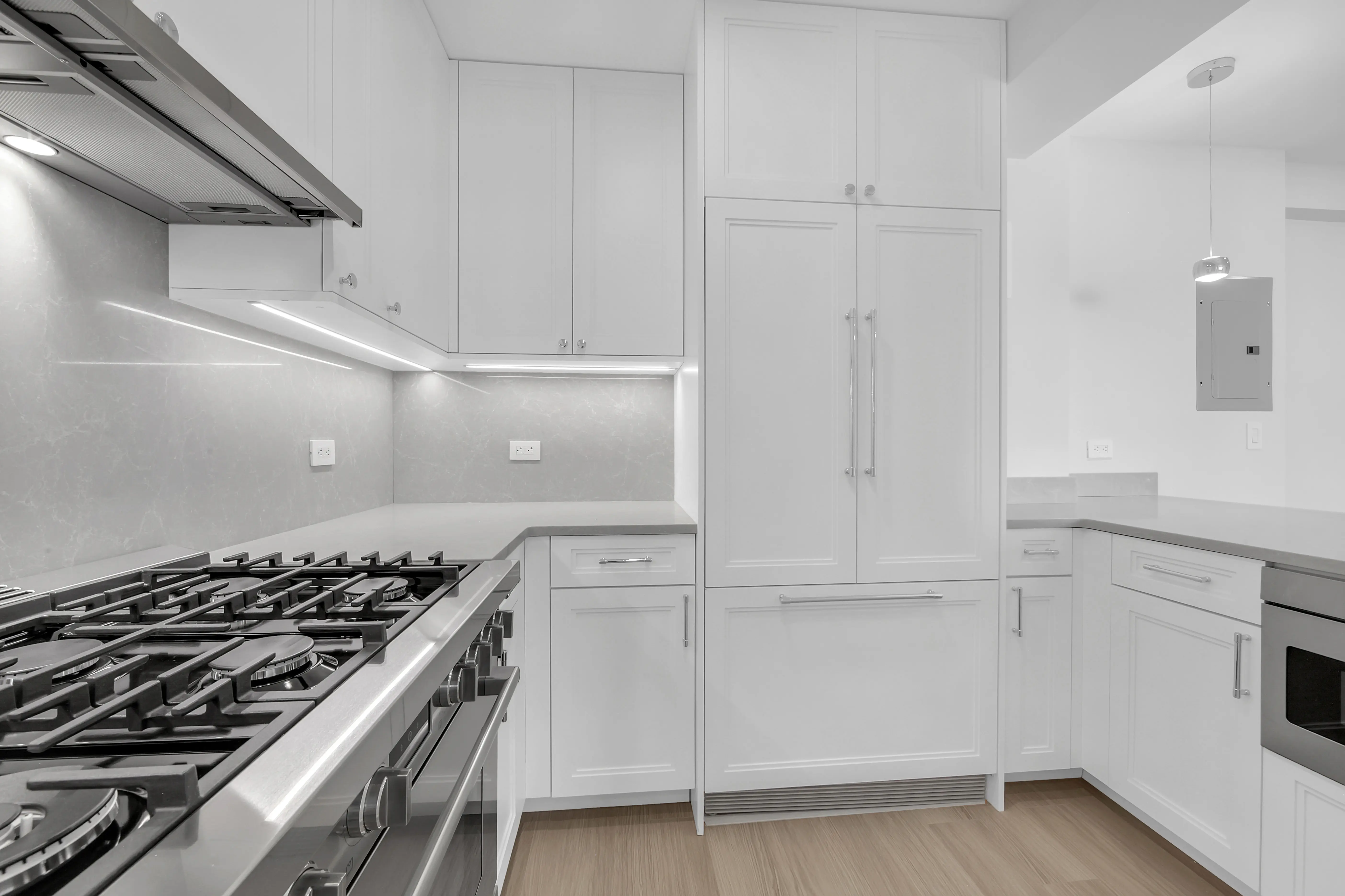 A bright white kitchen featuring modern stainless steel appliances and a clean, organized layout.