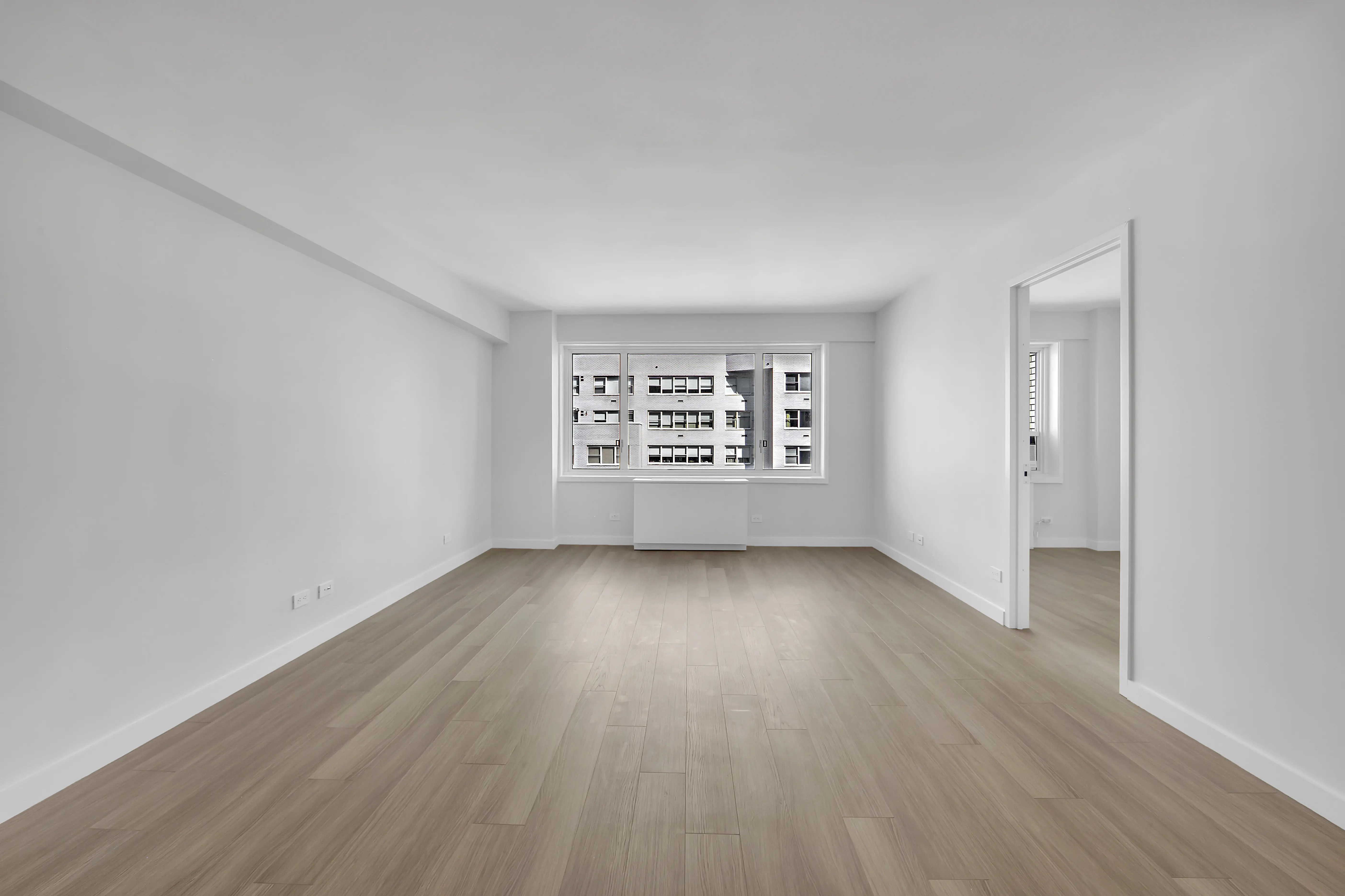 An empty room featuring hardwood floors and white walls, creating a bright and spacious atmosphere.