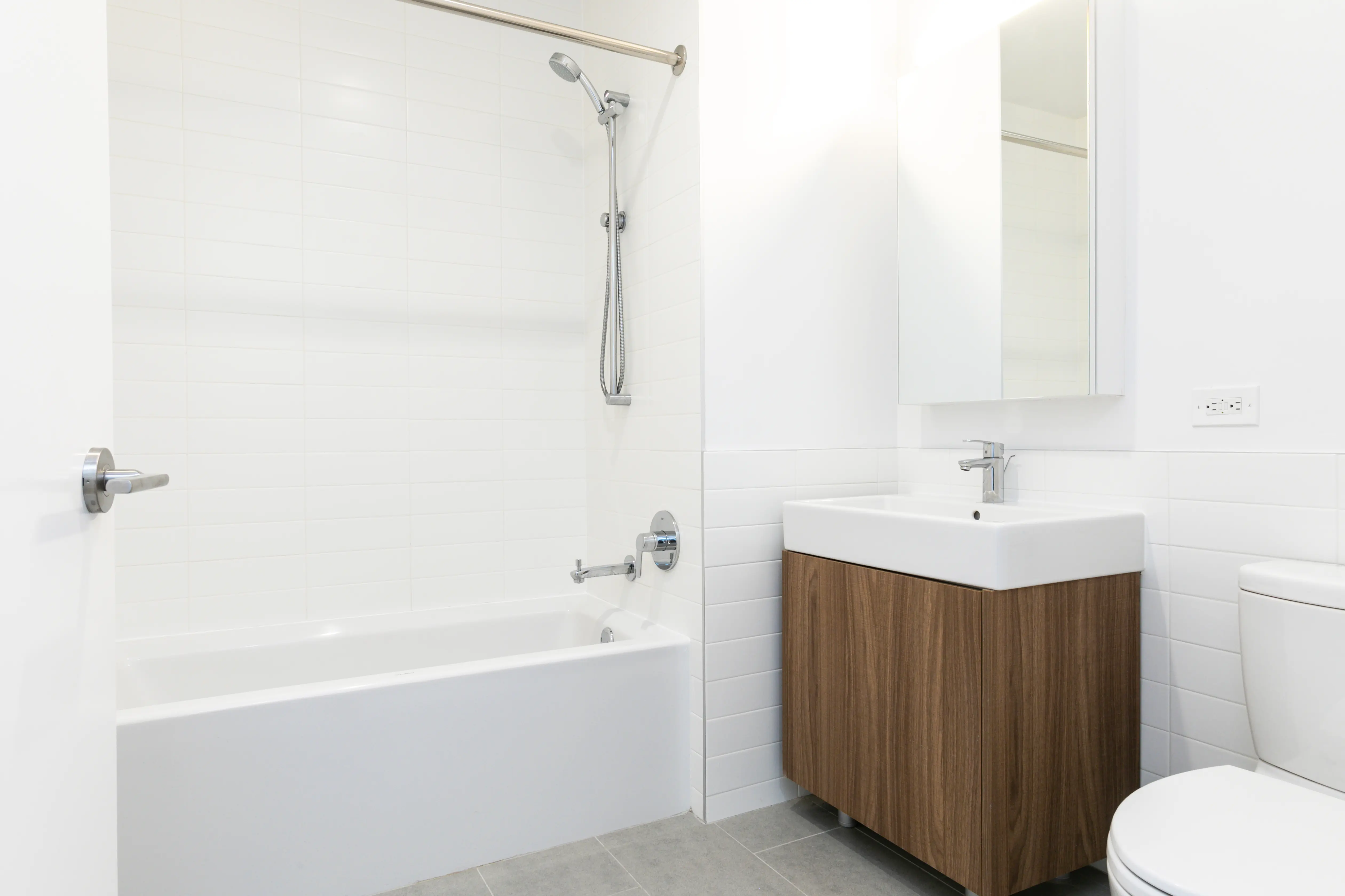 A spacious bathroom containing a toilet, sink, and bathtub, designed with contemporary decor and ample natural light.