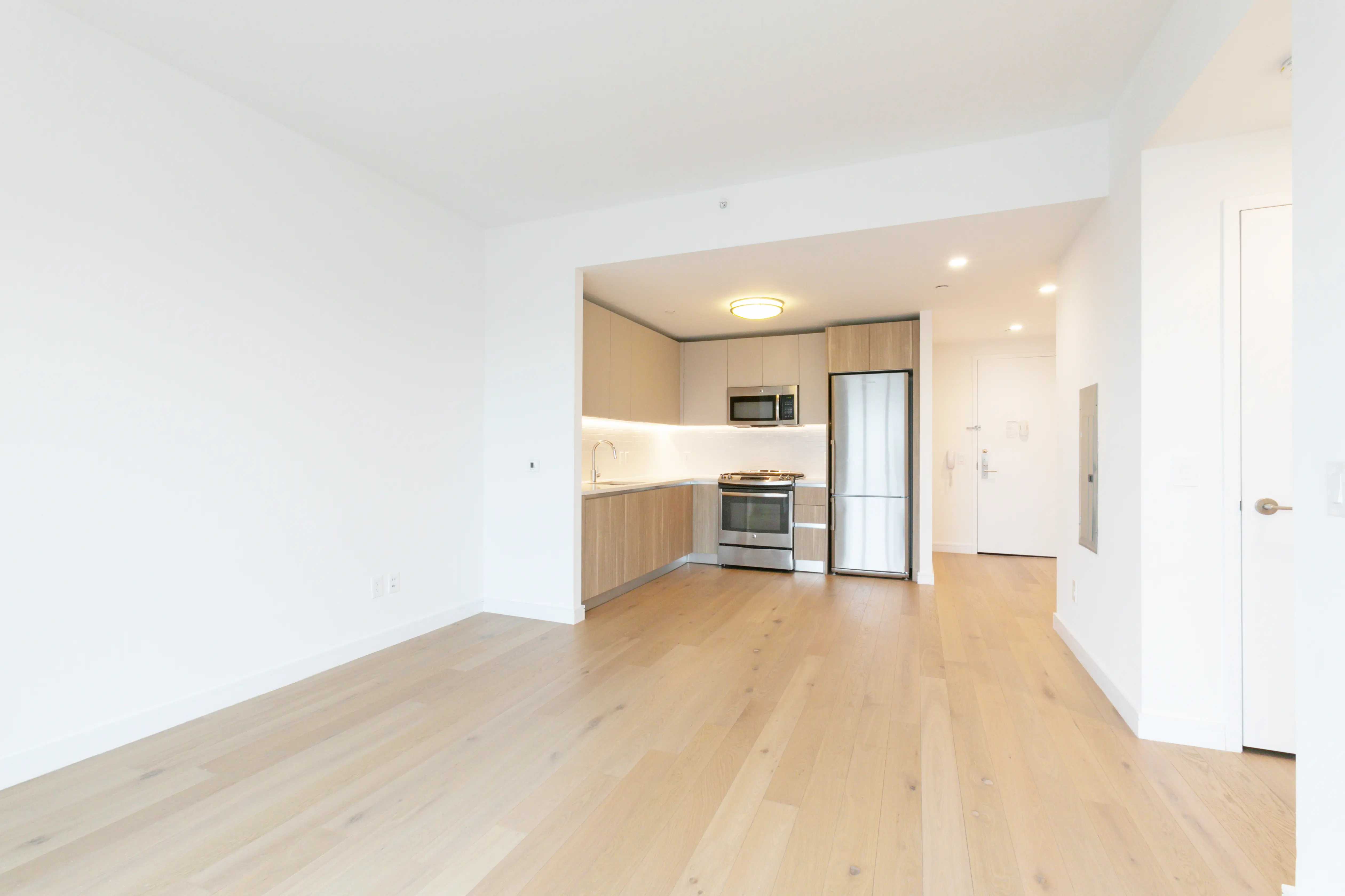 A bright white kitchen and living room featuring hardwood floors, showcasing a clean and modern design.