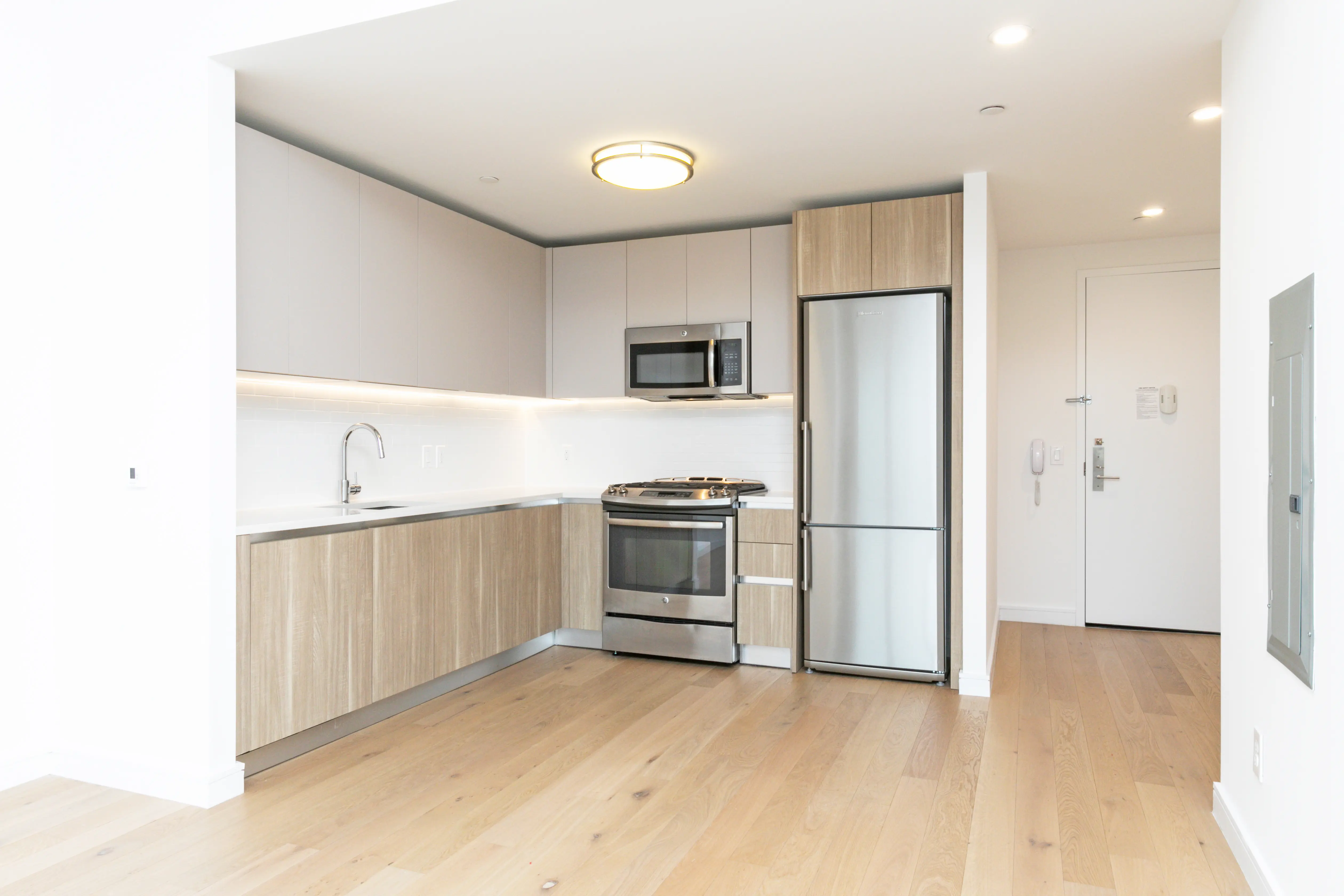 A modern kitchen featuring stainless steel appliances and warm wood floors, creating a stylish and inviting atmosphere.