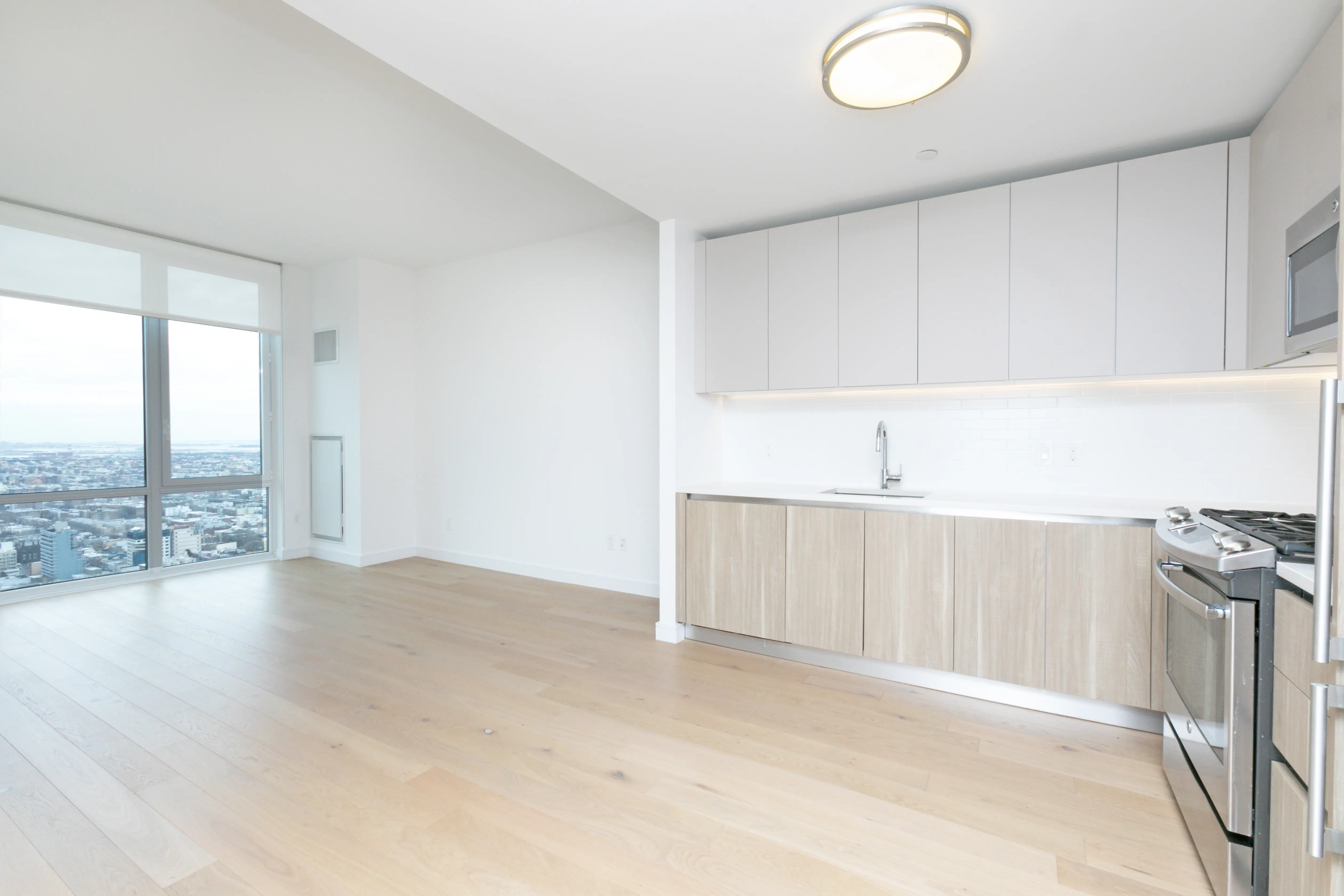 A modern kitchen featuring large windows with views of the city skyline and a serene body of water.