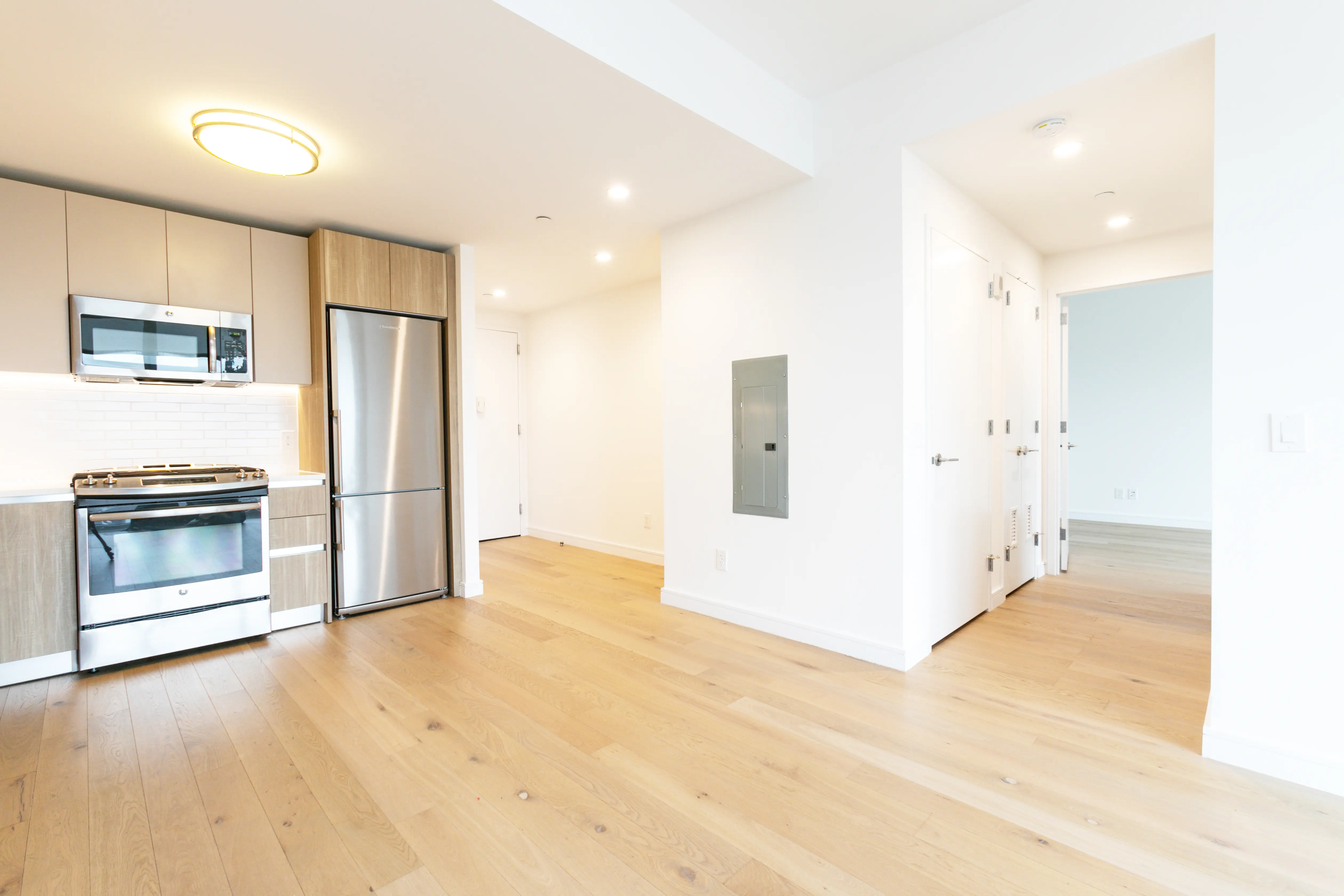 A contemporary kitchen with sleek stainless steel appliances and rich wooden flooring, offering a cozy and elegant look.