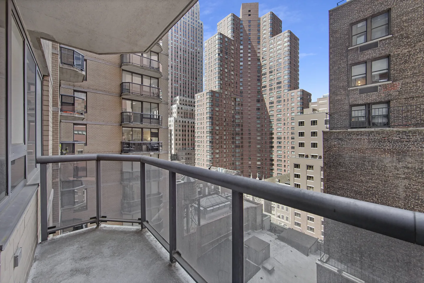 A balcony view showcasing a vibrant cityscape with towering buildings against a bright sky.
