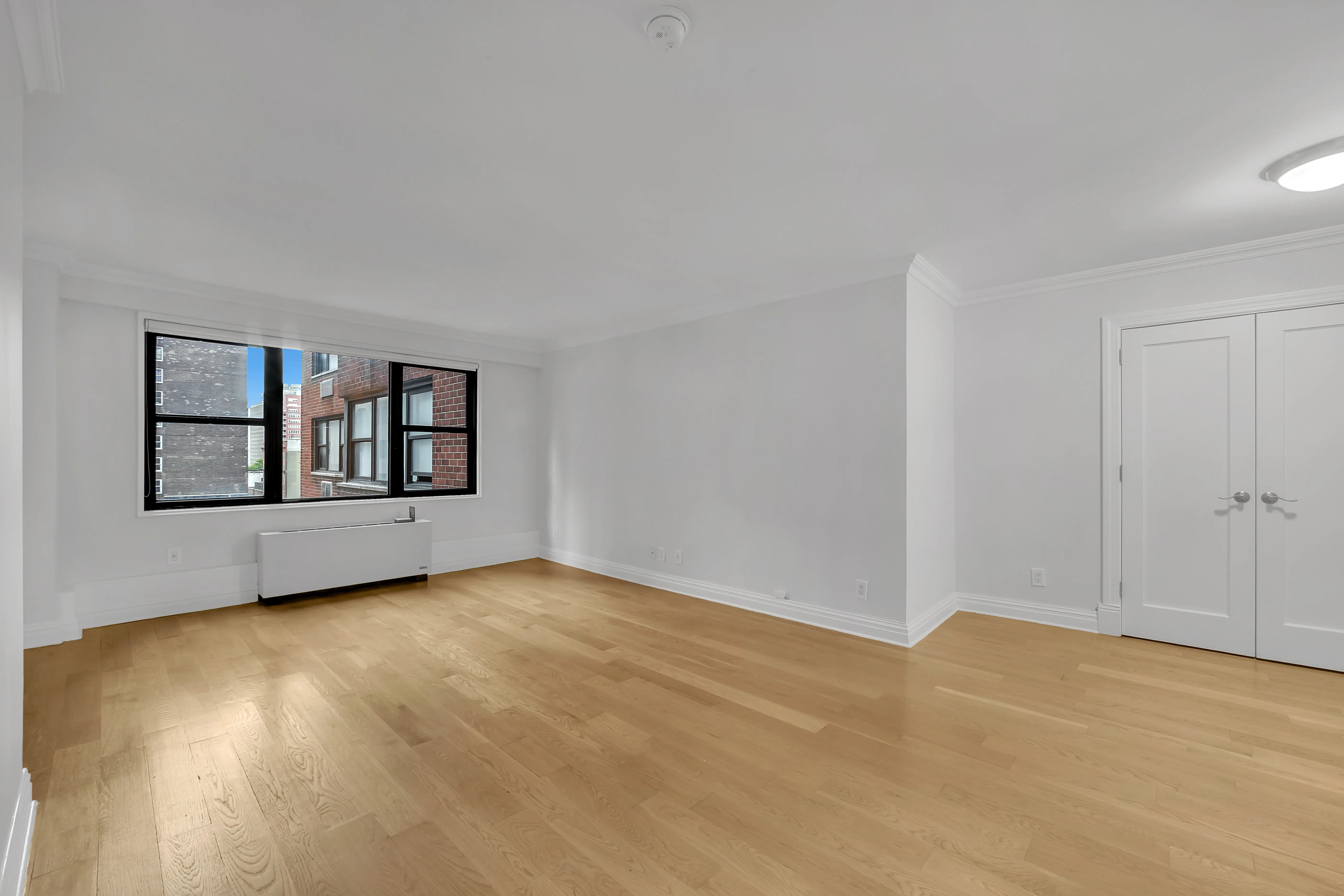 A vacant room with polished hardwood floors and clean white walls, offering a minimalist and open feel.