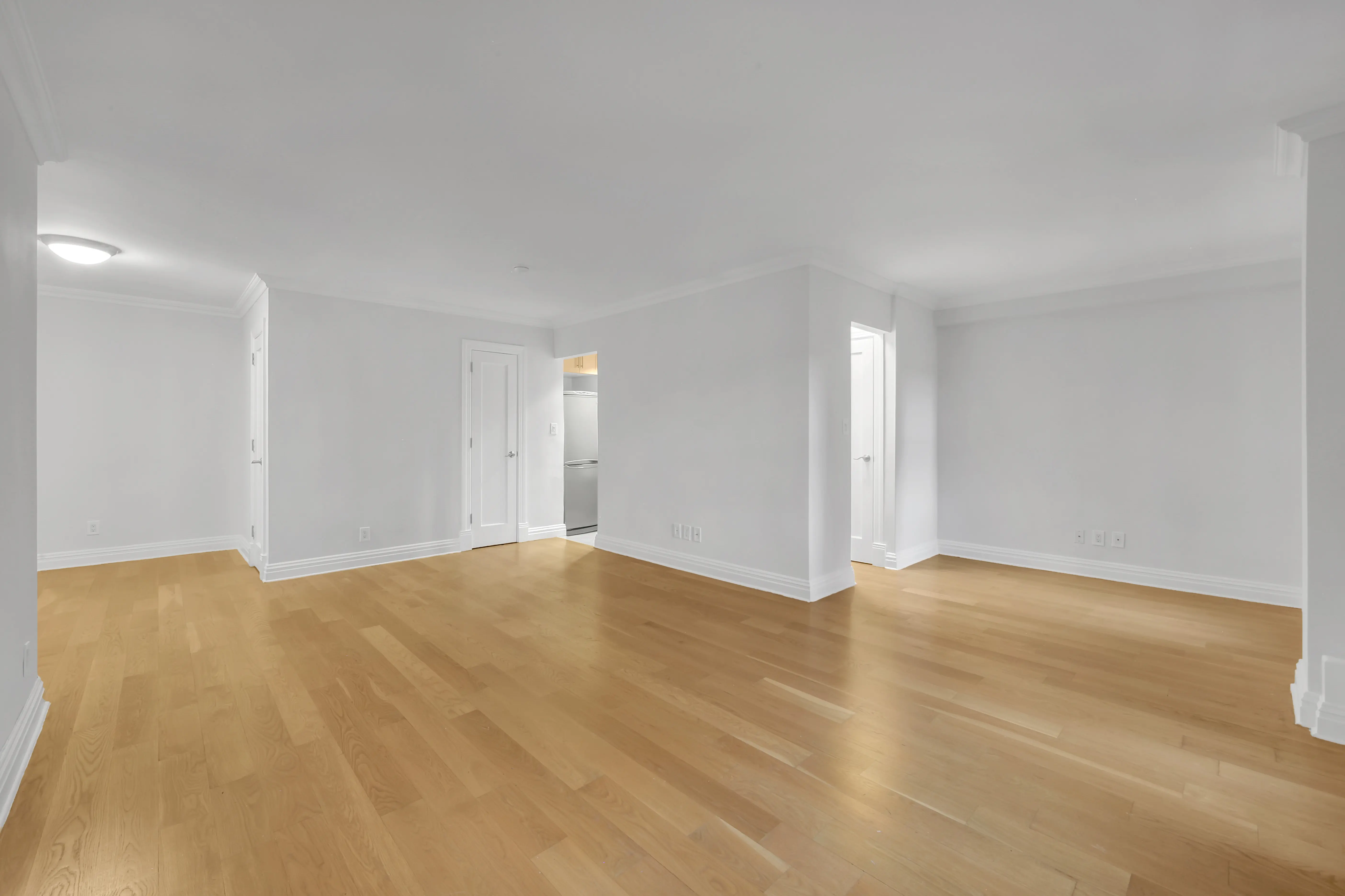 A vacant room with polished hardwood floors and clean white walls, offering a minimalist and open feel.