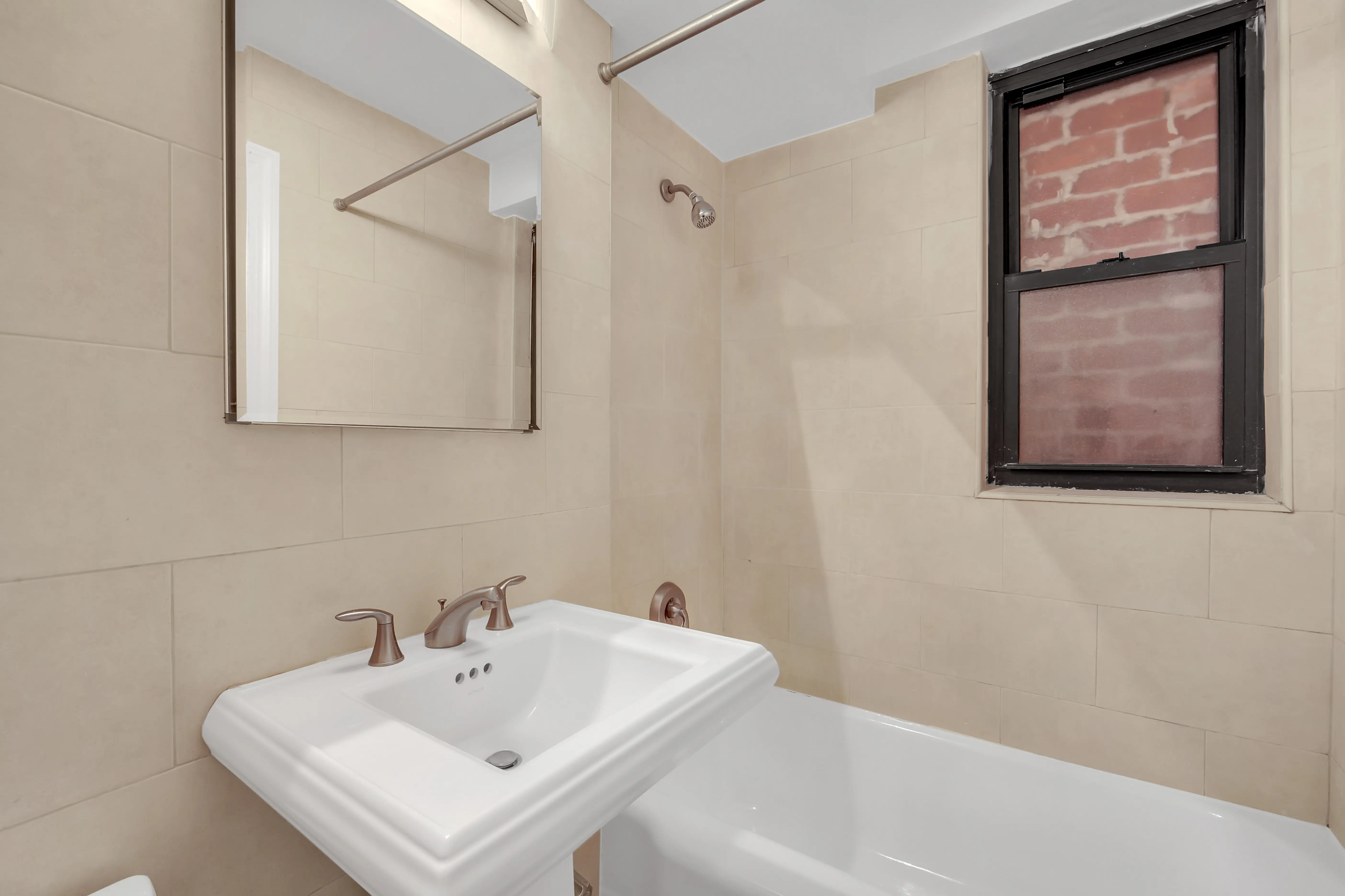 A clean bathroom showcasing a sink, toilet, and a window that enhances the room's brightness.