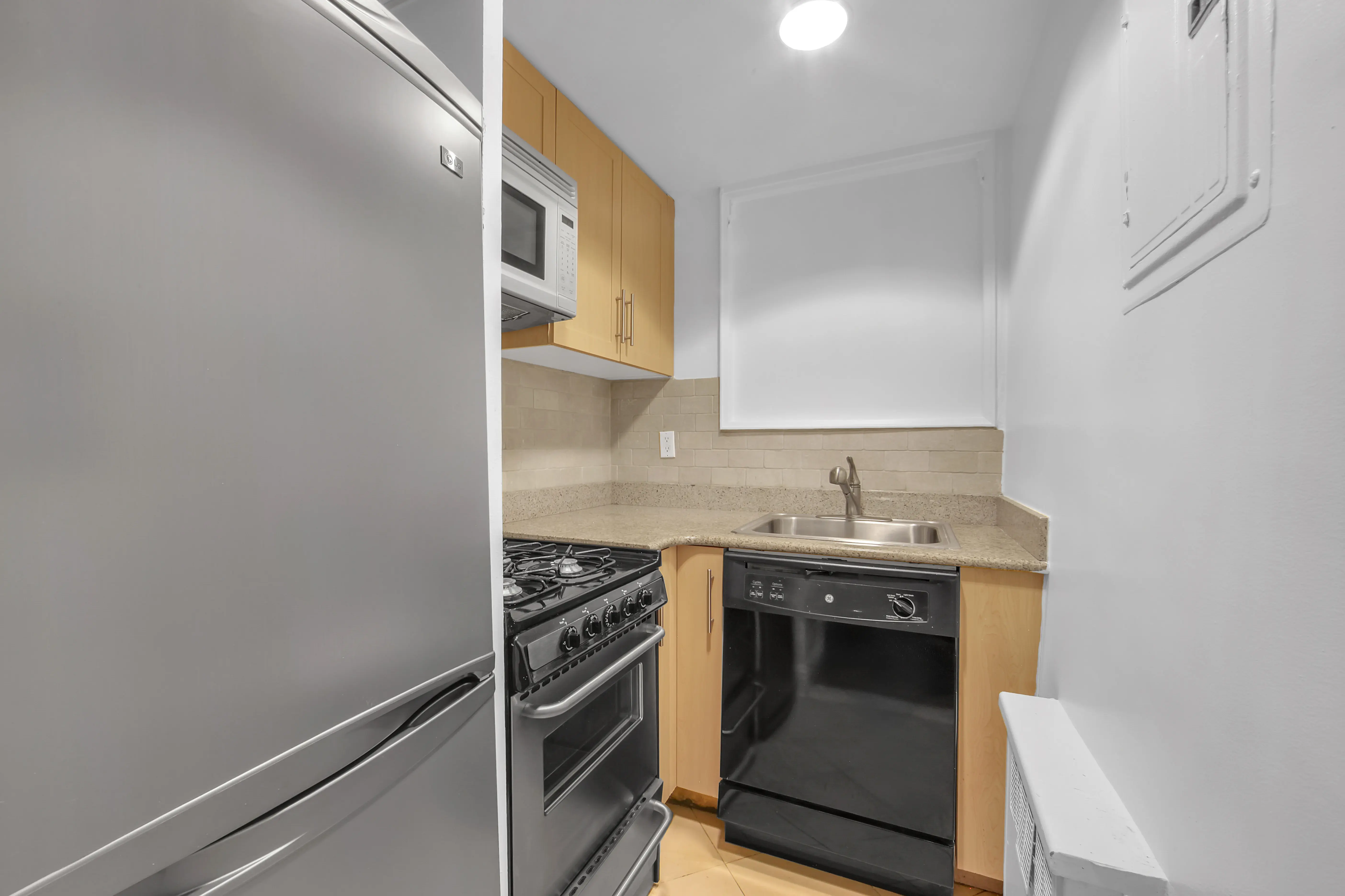 A compact kitchen featuring a refrigerator, stove, and microwave arranged for efficient use of space.