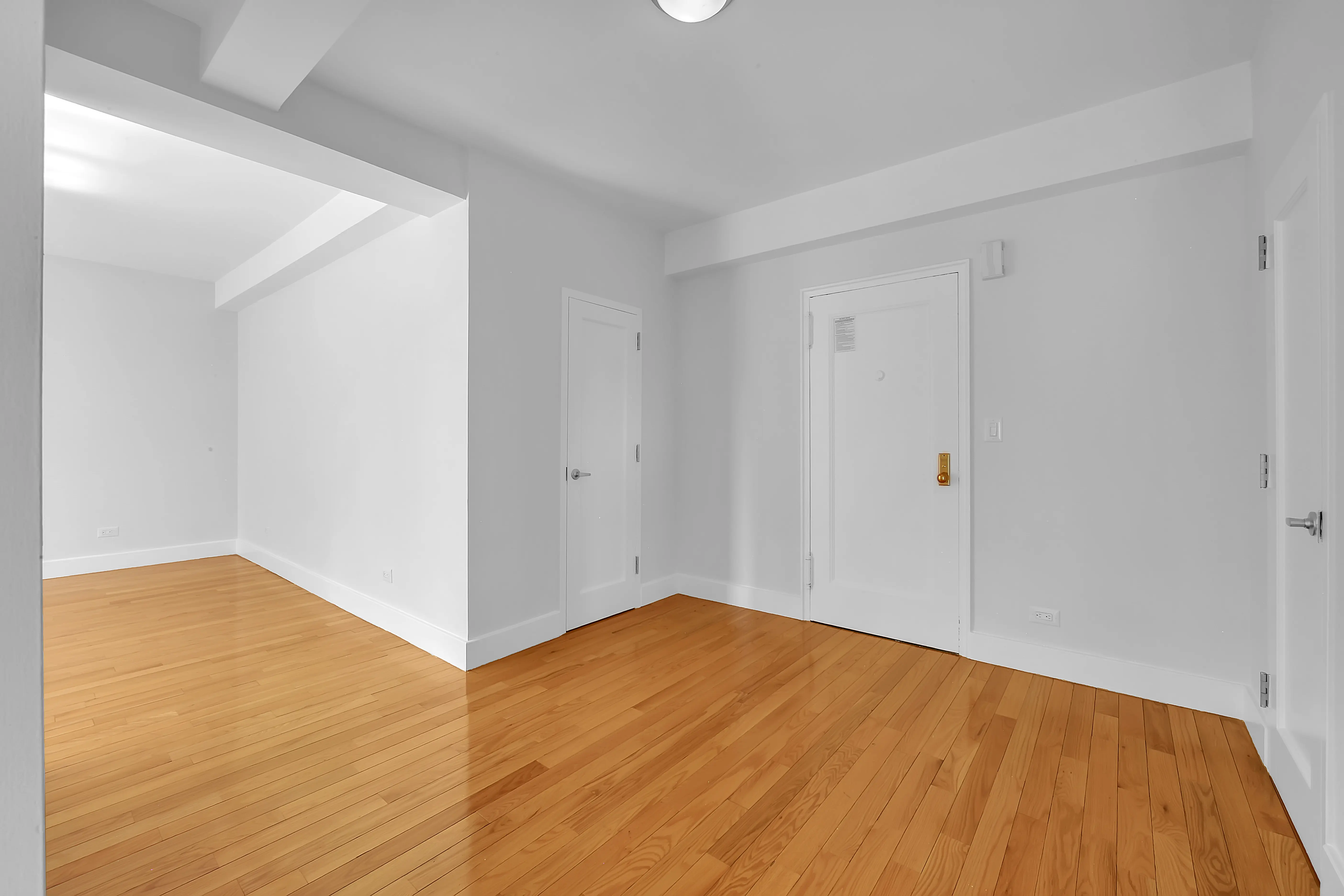 A vacant room with polished hardwood floors and clean white walls, offering a minimalist and open feel.