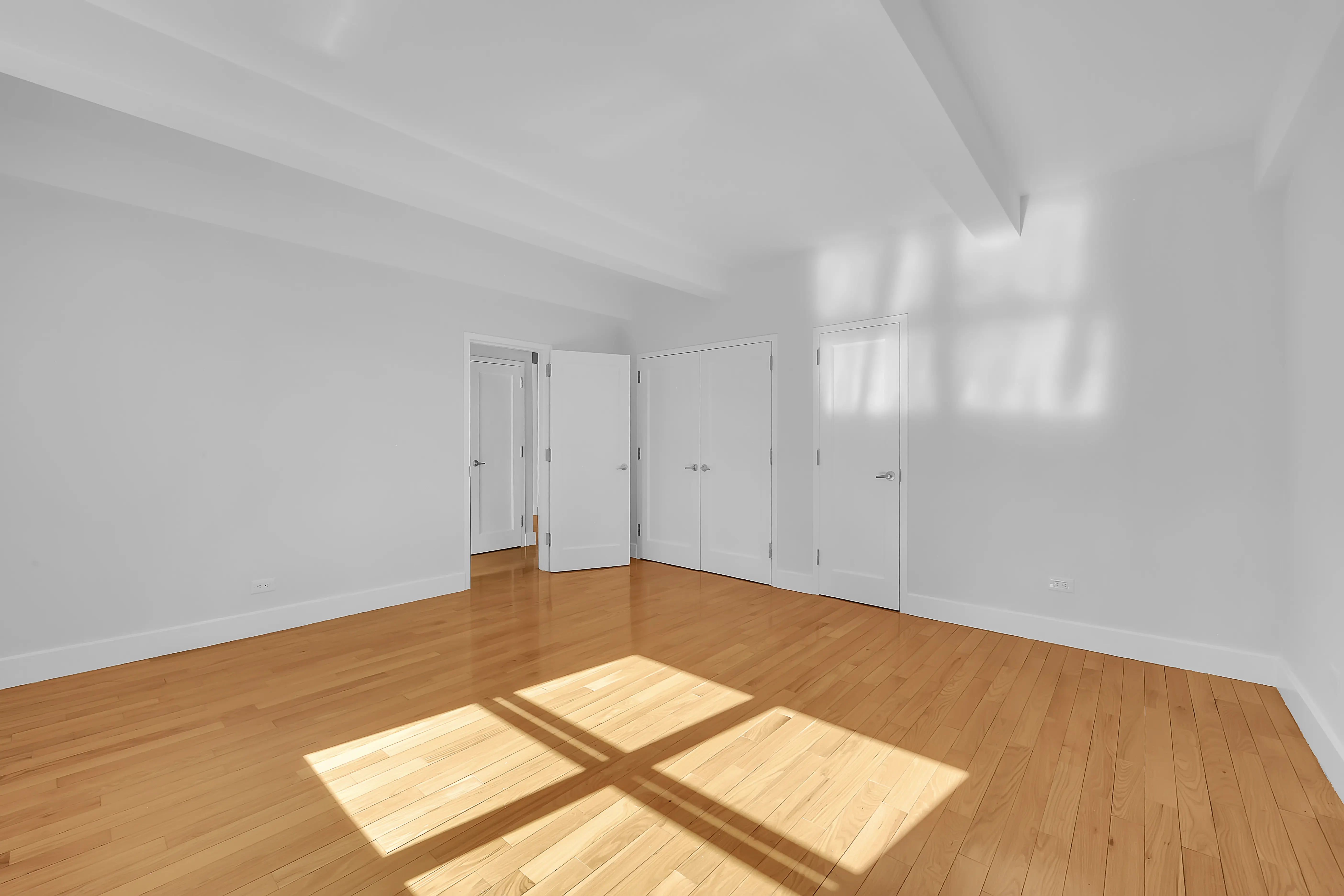 A vacant room with polished hardwood floors and clean white walls, offering a minimalist and open feel.