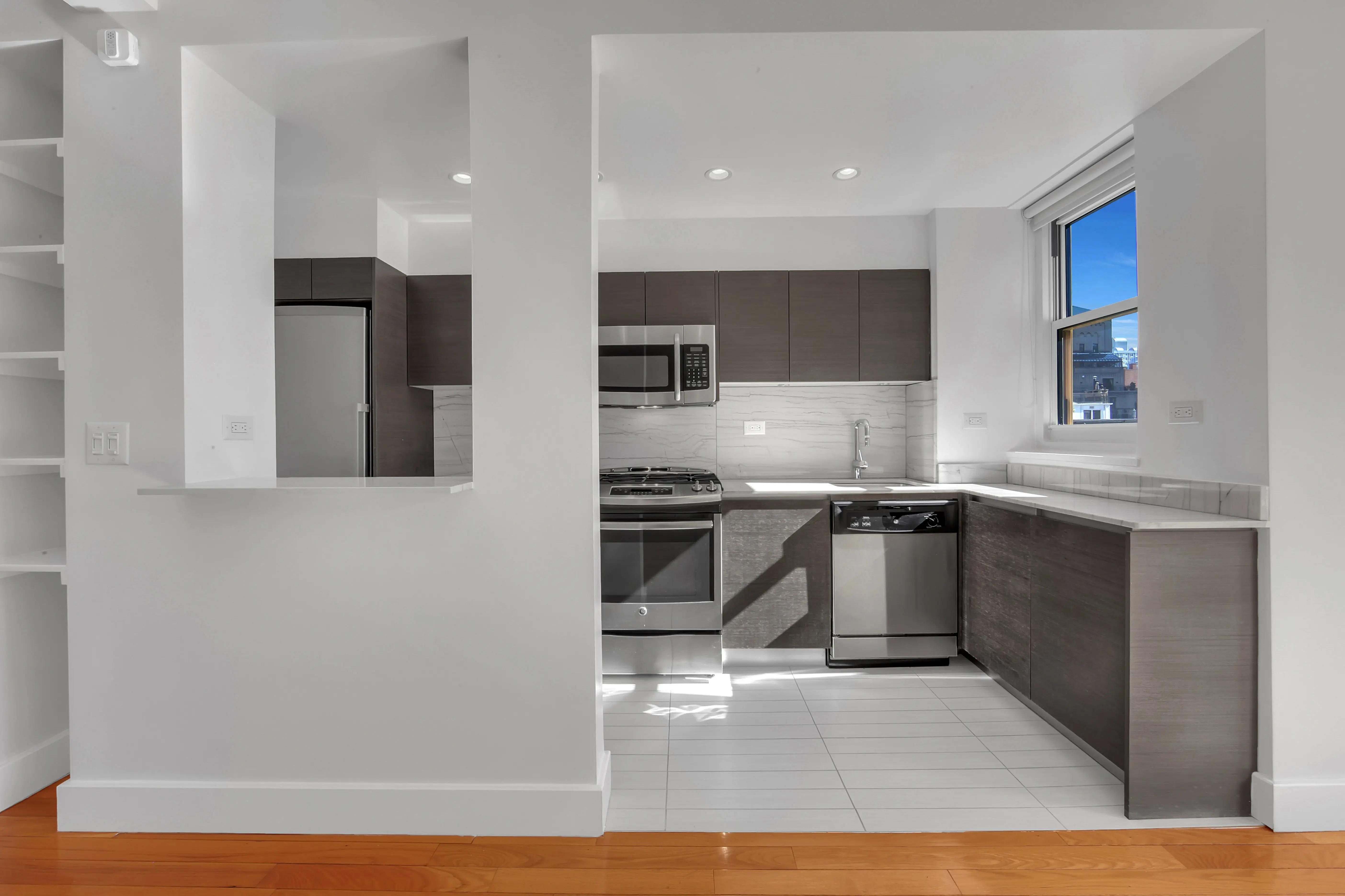 A modern kitchen featuring white cabinets and warm wooden floors, creating a bright and inviting atmosphere.